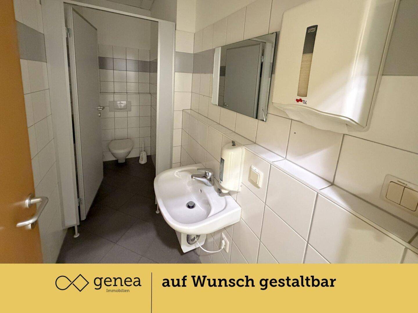 Toilettenraum mit Waschbecken und Spiegel, gefliest und mit Spender ausgestattet.
