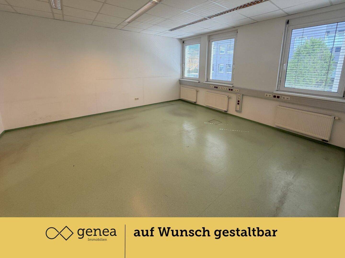 Geräumiges Büro mit großen Fenstern, hellem Licht und grünem Bodenbelag, bereit zur individuellen Gestaltung.