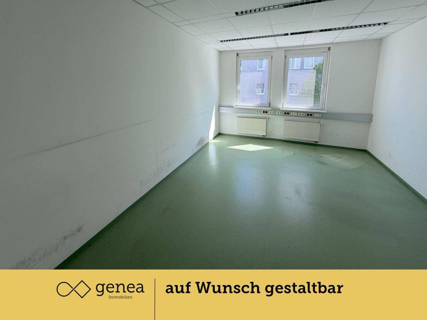 Heller Büroraum mit zwei Fenstern, grünem Bodenbelag und weißen Wänden.