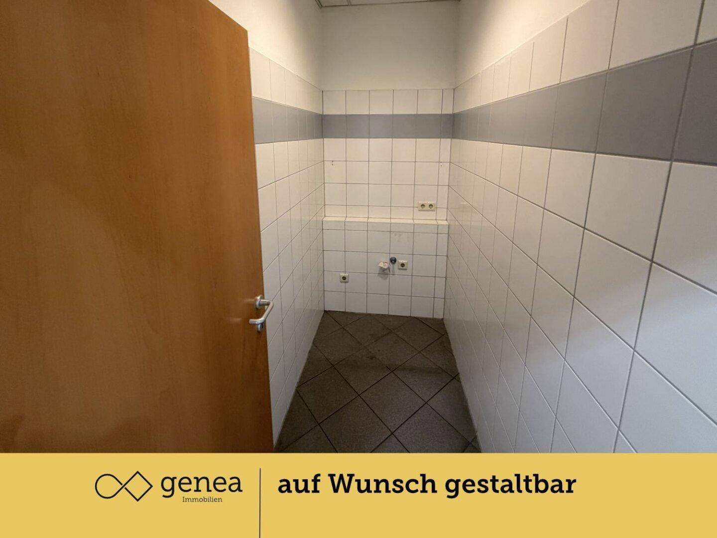 Leerer Toilettenraum mit weißen und grauen Wandfliesen sowie dunklem Fliesenboden, bereit für die Ausstattung.