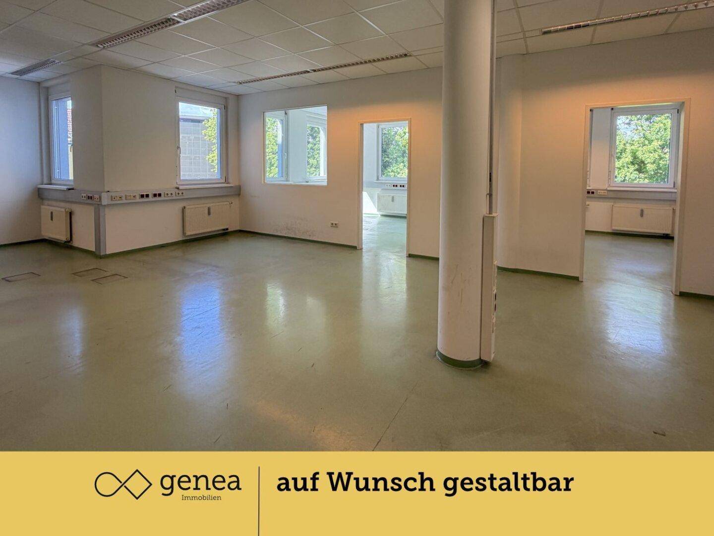 Großer, offener Bürobereich mit Säule, mehreren Fenstern und grünem Bodenbelag.