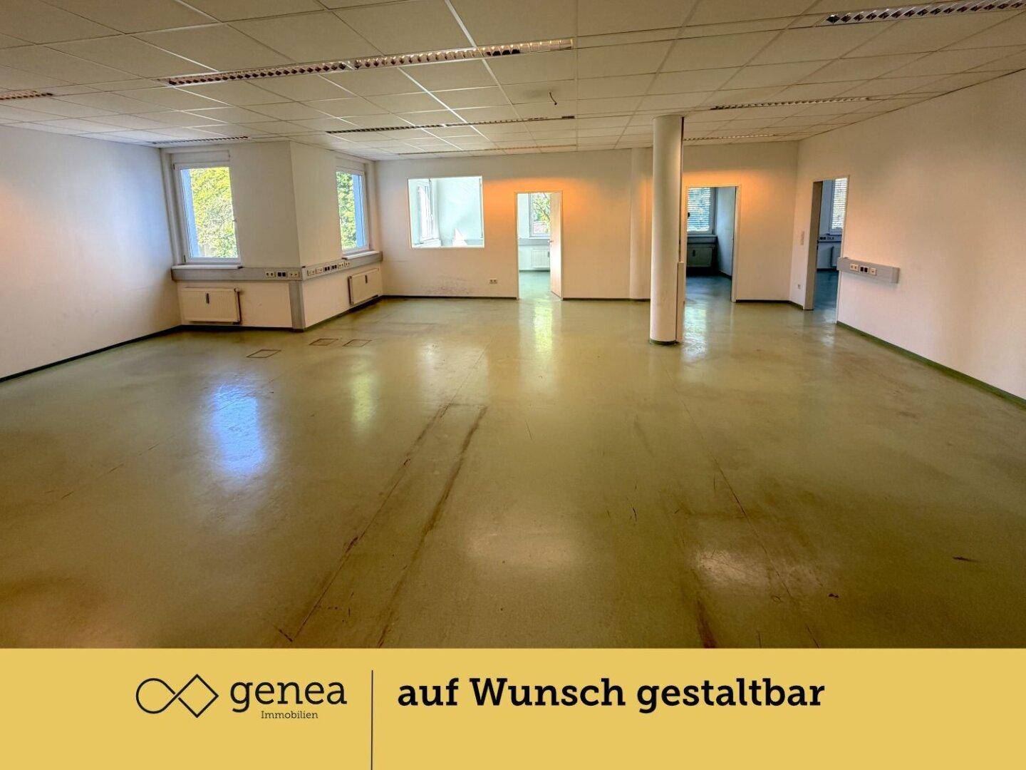 Geräumiger, leerer Büroraum mit großen Fenstern, Säule und Zugang zu weiteren Bereichen.