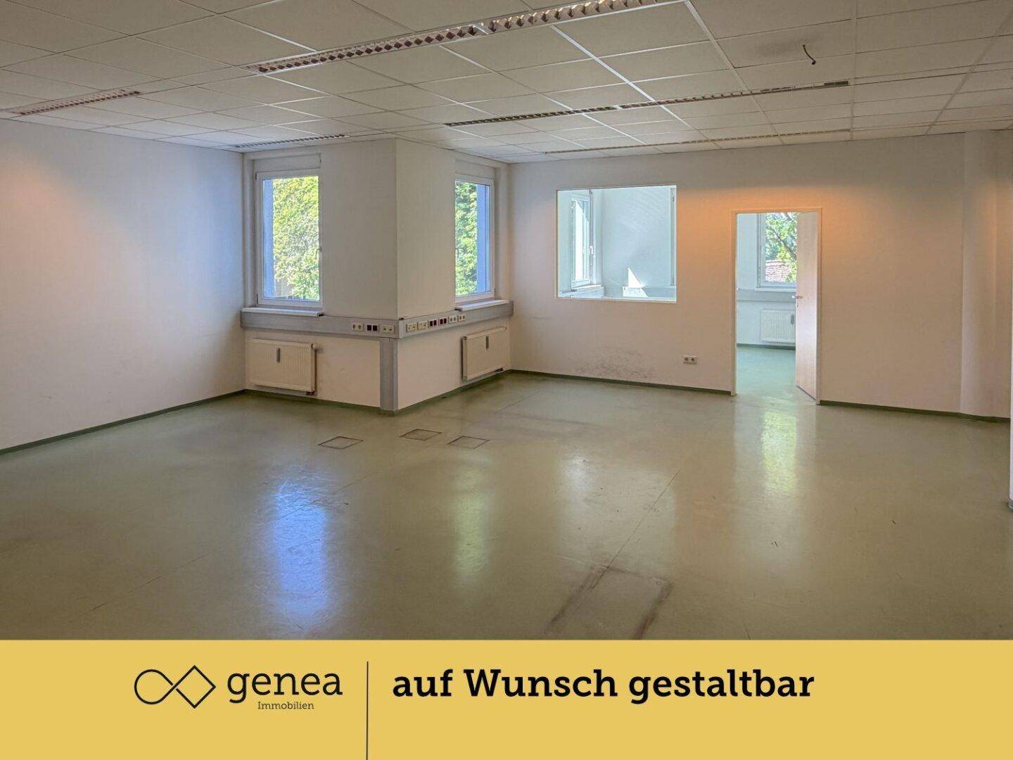 Großer, offener Bürobereich mit Säule, mehreren Fenstern und grünem Bodenbelag.