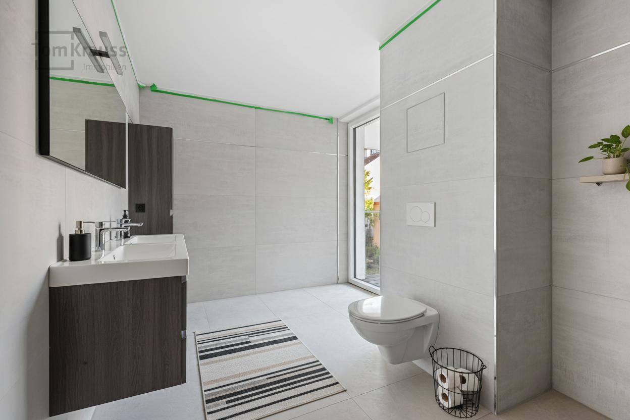 Modernes Badezimmer mit hellen Fliesen, Einzelwaschbecken und wandhängendem WC.