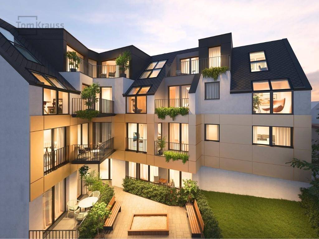Abendliche Ansicht eines modernen Wohnkomplexes mit begrüntem Innenhof und Balkonen.