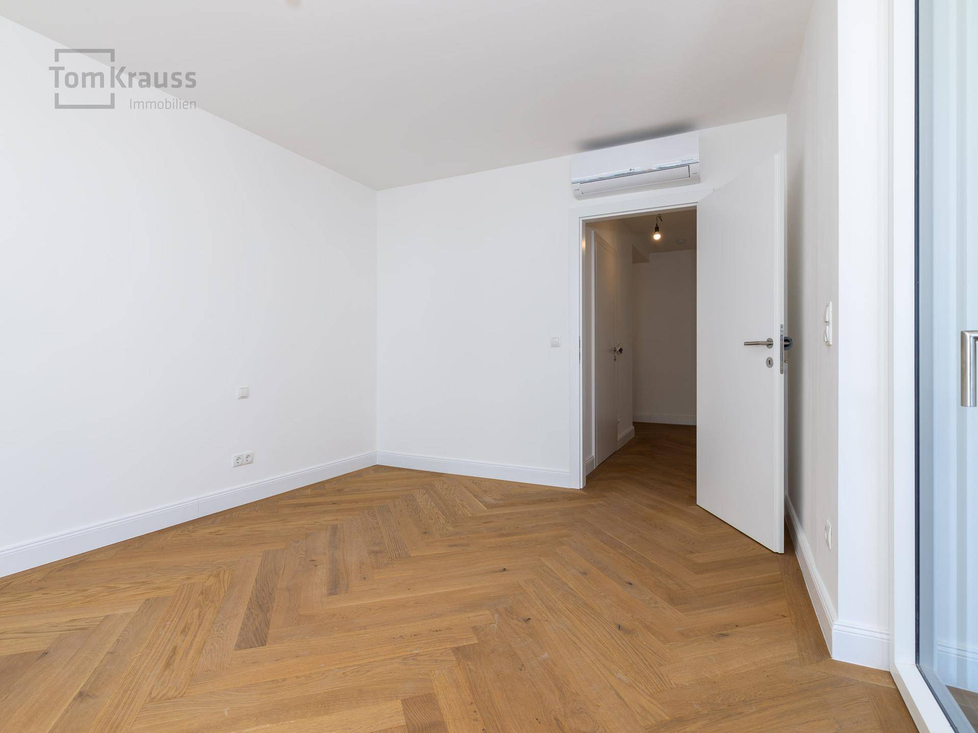 Helles Zimmer mit Fischgrätparkett und Klimaanlage, ideal für Schlaf- oder Wohnbereich.