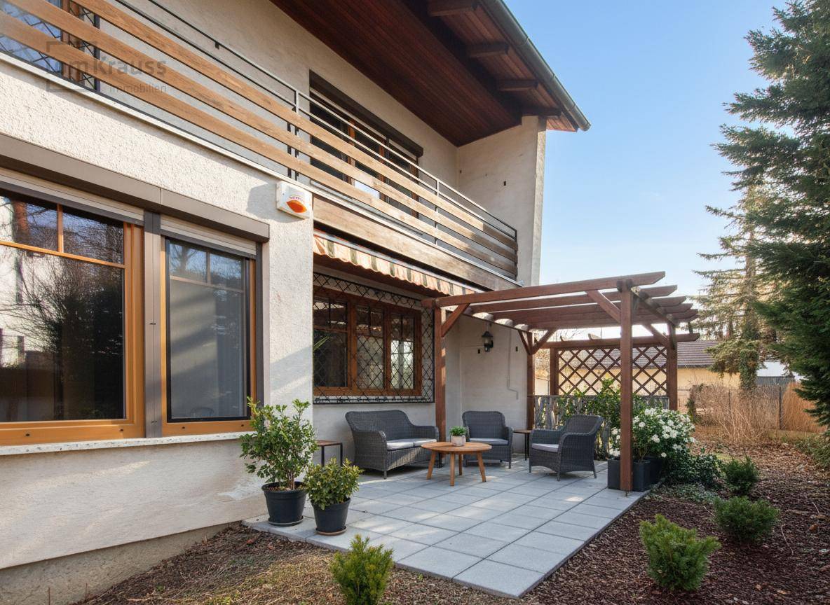 Renovierte Terrasse mit Pflastersteinen, Gartenmöbeln unter einer Pergola und gepflegtem Garten.