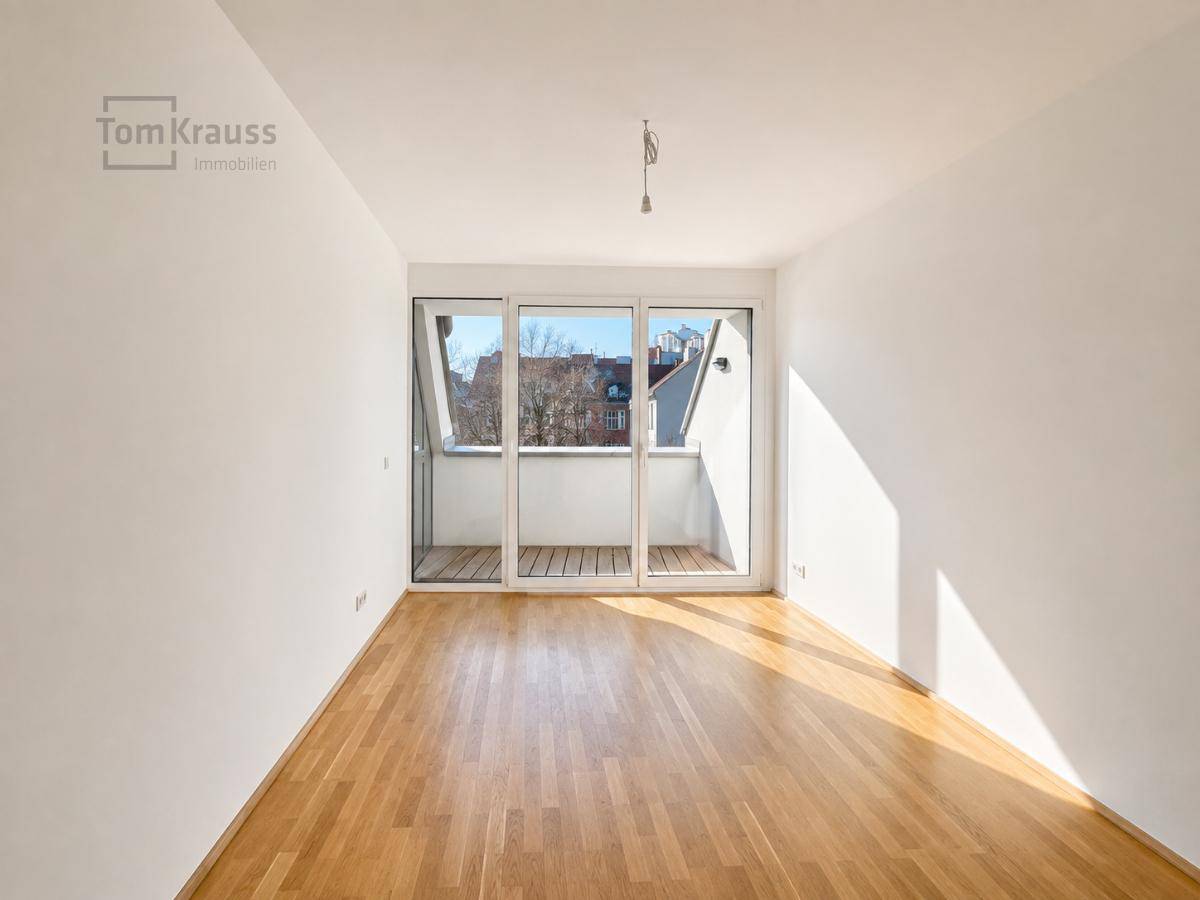 Leeres Schlafzimmer mit hellem Parkettboden und Zugang zu einem kleinen Außenbereich.