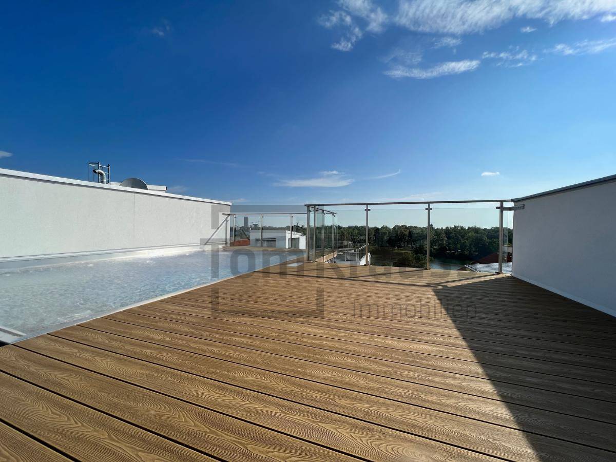 Geräumige Dachterrasse mit Holzboden und Glasgeländer bietet weiten Blick auf die Umgebung.