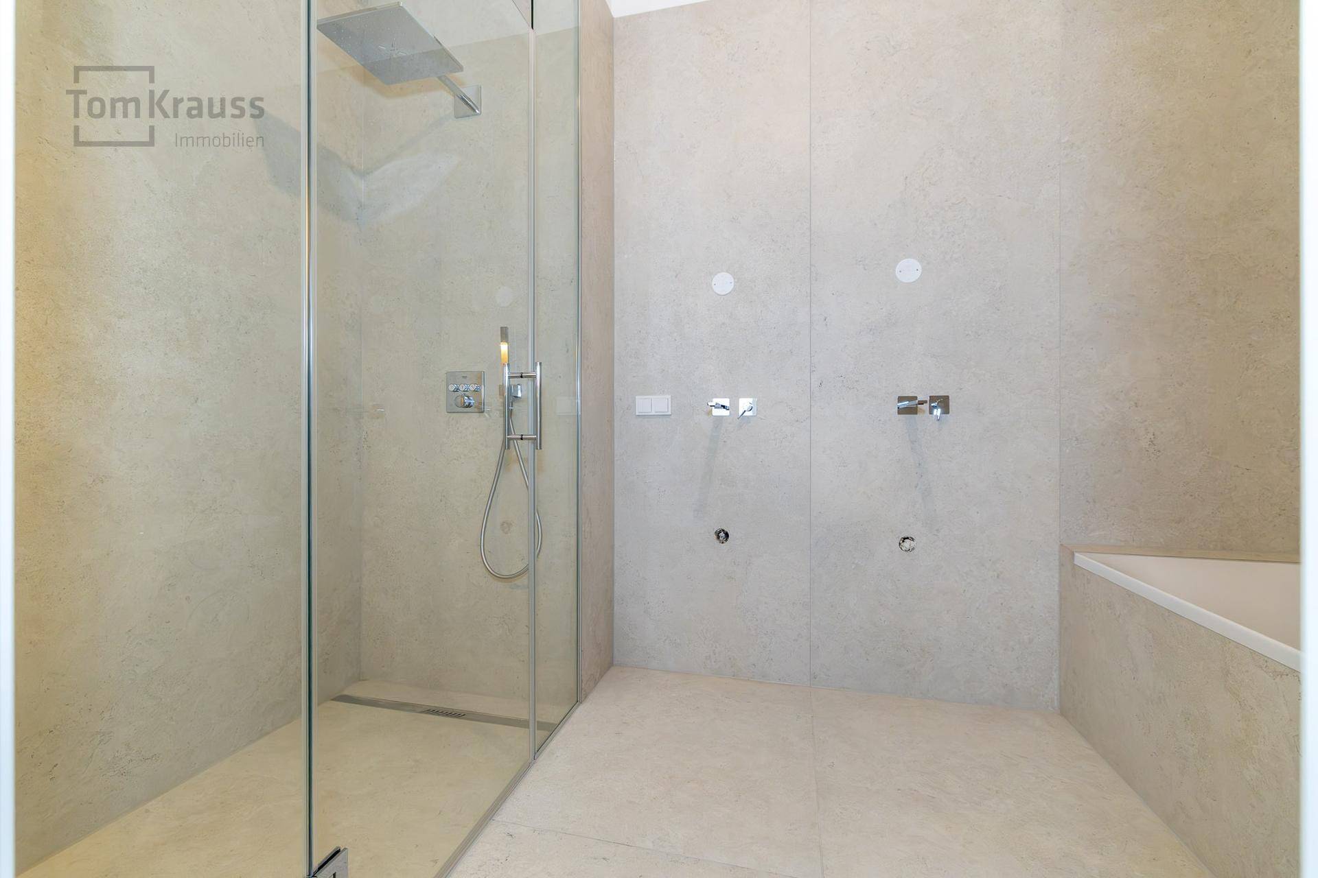 Helles Badezimmer mit Fliesenboden und -wänden, vorbereitet für Dusche und Badewanne.