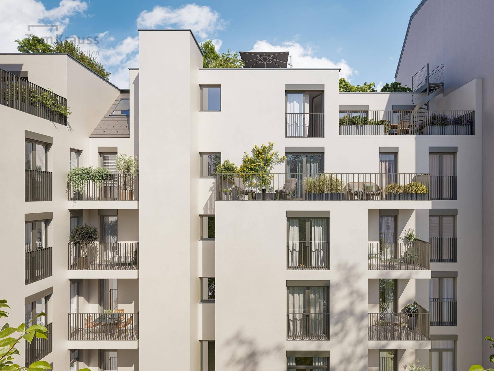 Moderne Wohnanlage mit mehreren Balkonen und begrünten Terrassen unter klarem Himmel.