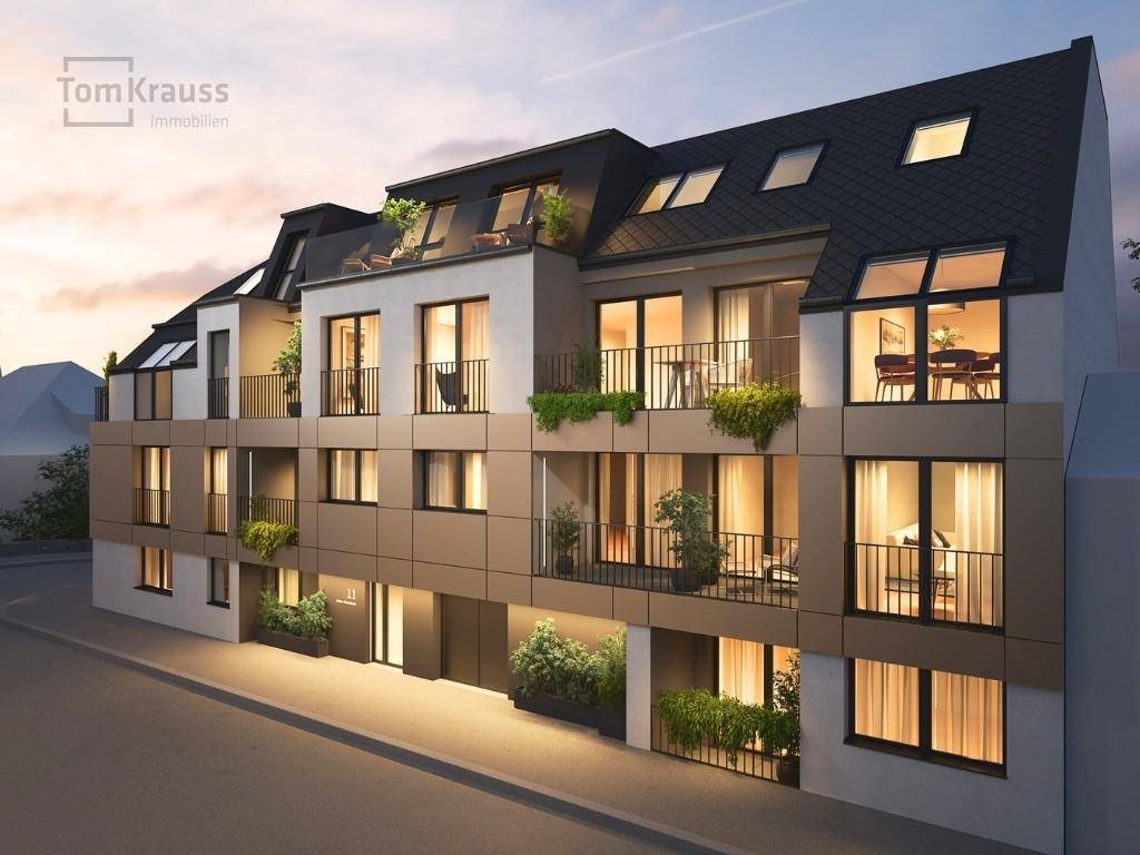 Abendliche Ansicht der modernen Fassade eines Wohngebäudes mit beleuchtetem Eingangsbereich.