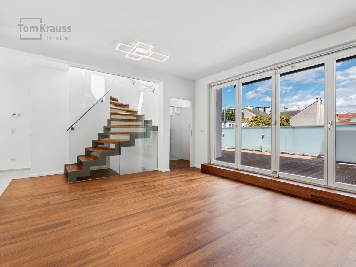 Helles Wohnzimmer mit Holzboden, großer Fensterfront und Zugang zu einer Terrasse.