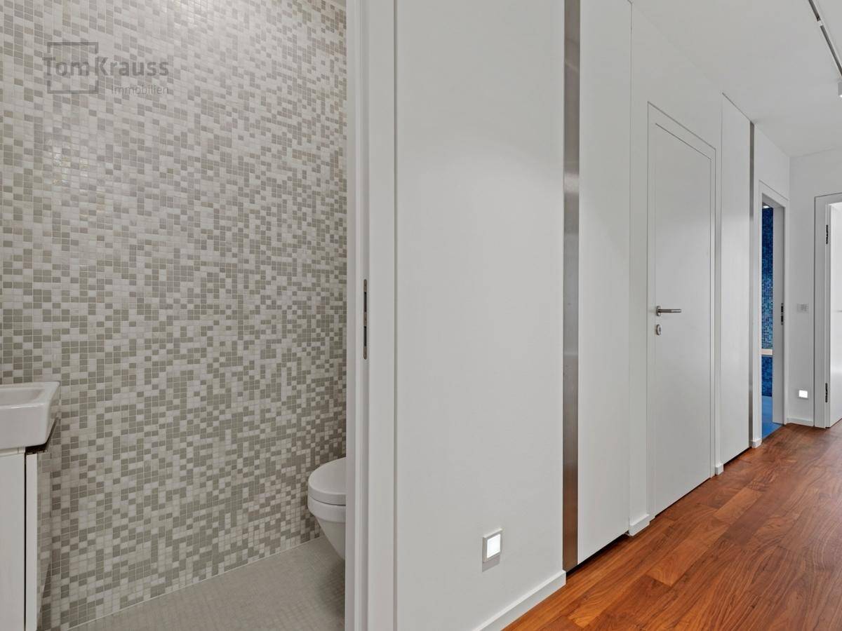 Modernes Gäste-WC mit Mosaikfliesen und wandmontierter Toilette.