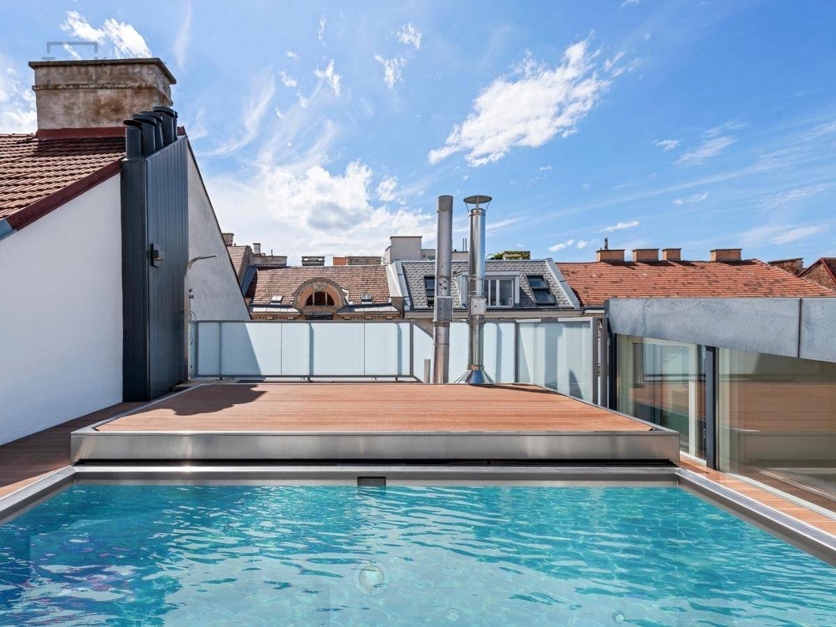 Dachterrasse mit eingelassenem Pool und Holzdeck, umgeben von historischen Dächern.