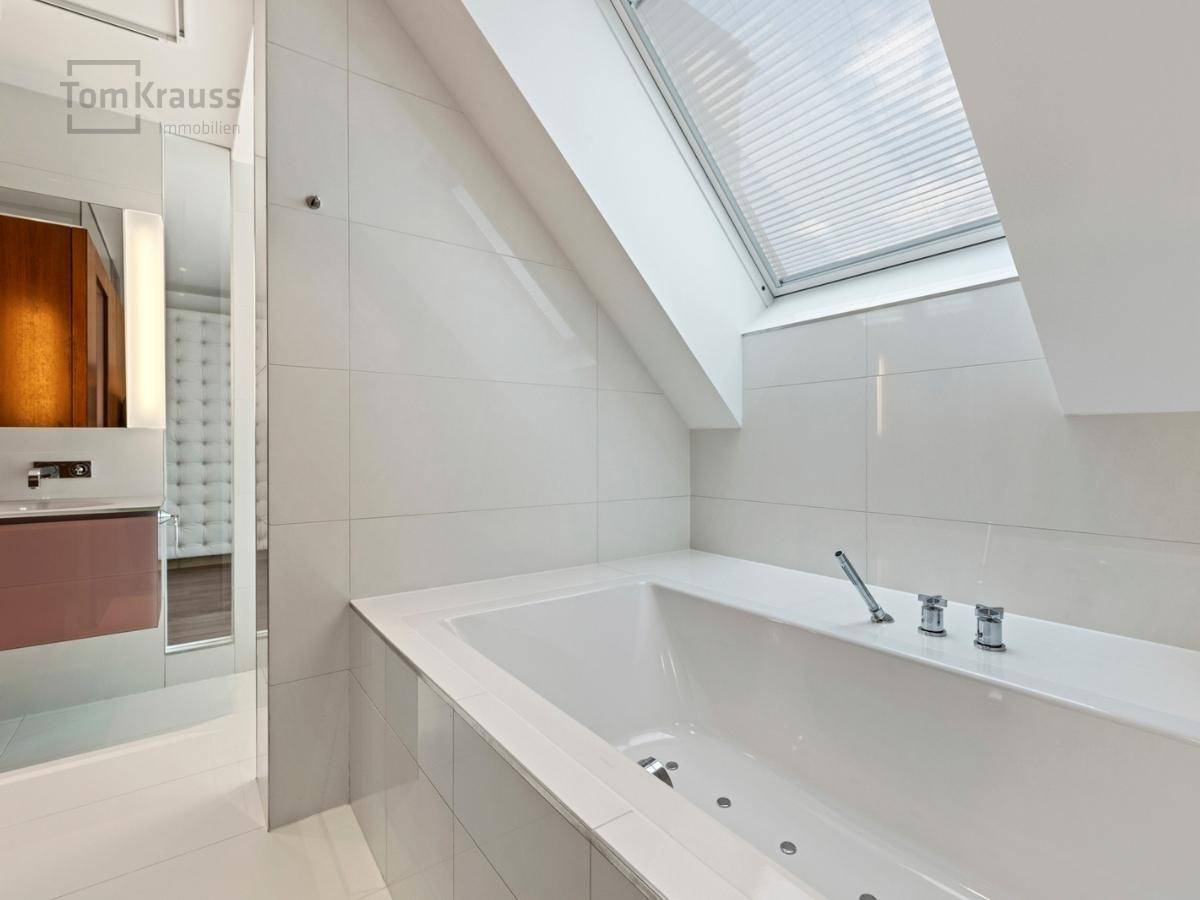 Elegantes Badezimmer mit Badewanne, Dachfenster und modernen Fliesen.