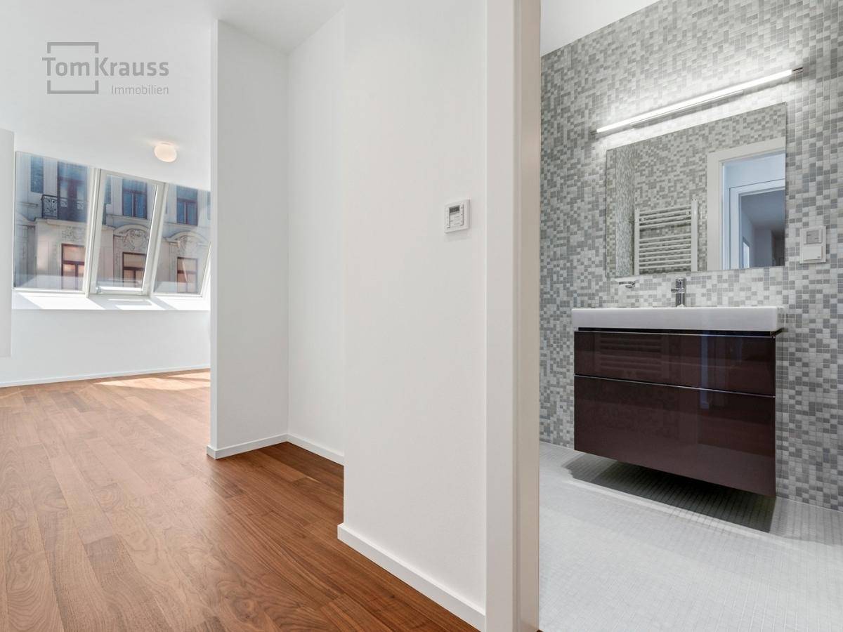 Moderner Badezimmerbereich mit Mosaikfliesen, Waschtisch und Spiegel.