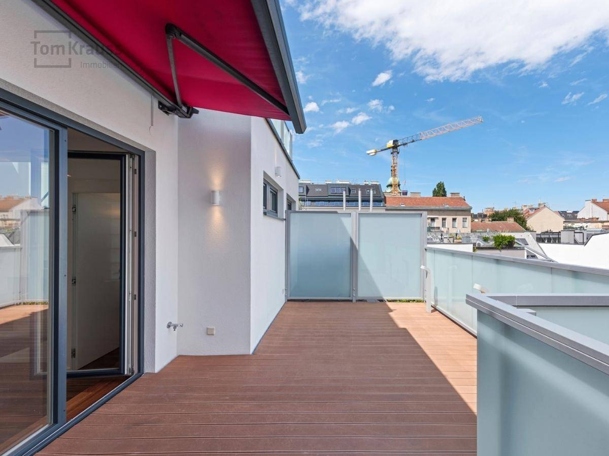 Geräumige Terrasse mit Holzdeck, Markise und Blick auf die Umgebung.