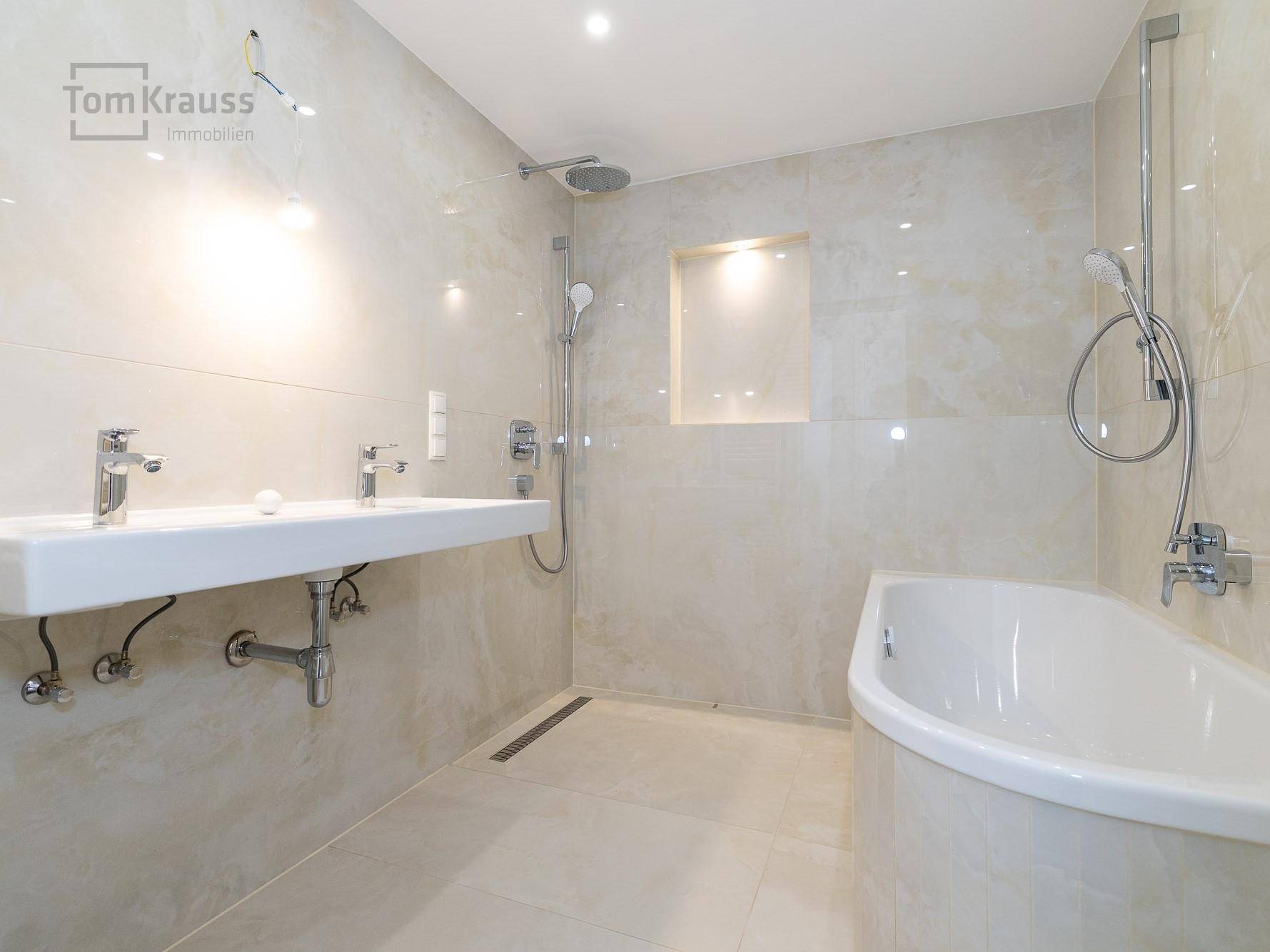 Modernes Badezimmer mit Doppelwaschbecken, Badewanne und begehbarer Dusche, hell gefliest.