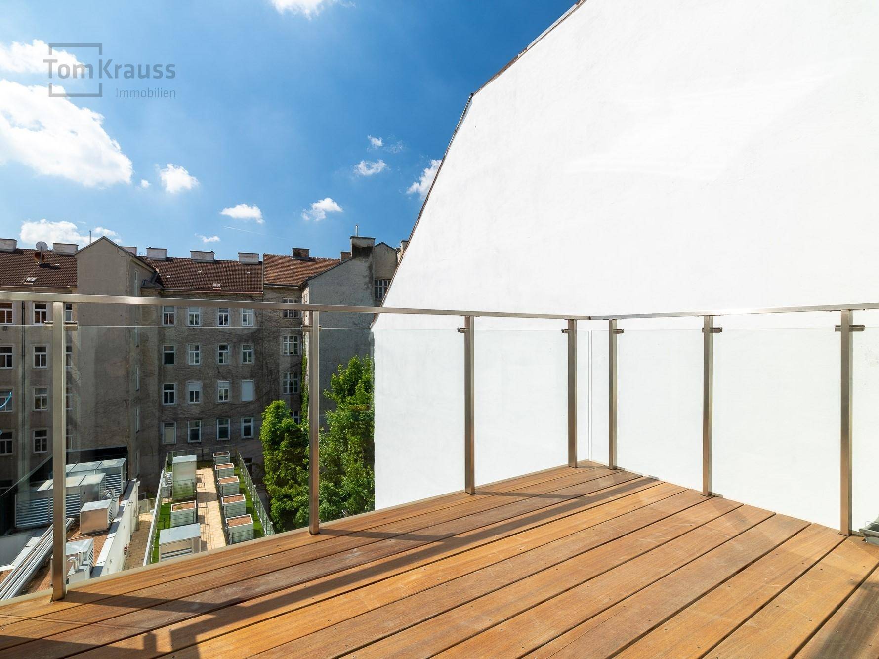 Geräumiger Balkon mit Holzboden und modernem Glasgeländer, bereit zur individuellen Gestaltung.