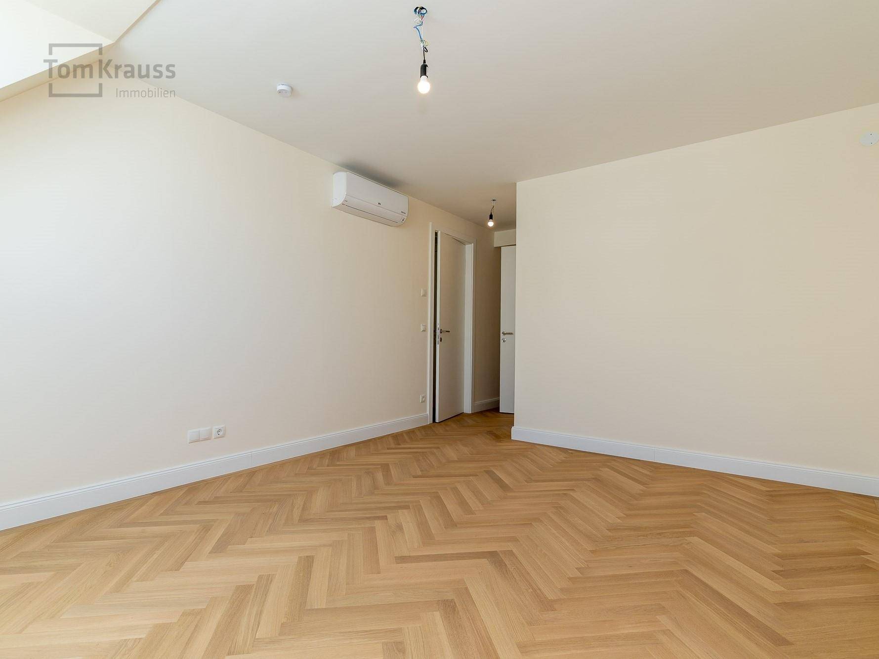 Heller Raum mit Fischgrätparkett, Klimaanlage und Dachfenstern, ideal als Schlaf- oder Arbeitszimmer.