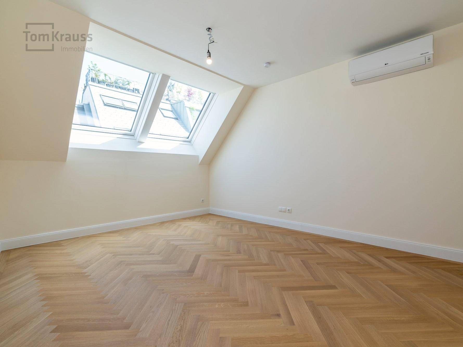 Helles Schlafzimmer mit Fischgrätparkett, Dachfenstern und Klimaanlage, bietet viel Gestaltungspotenzial.