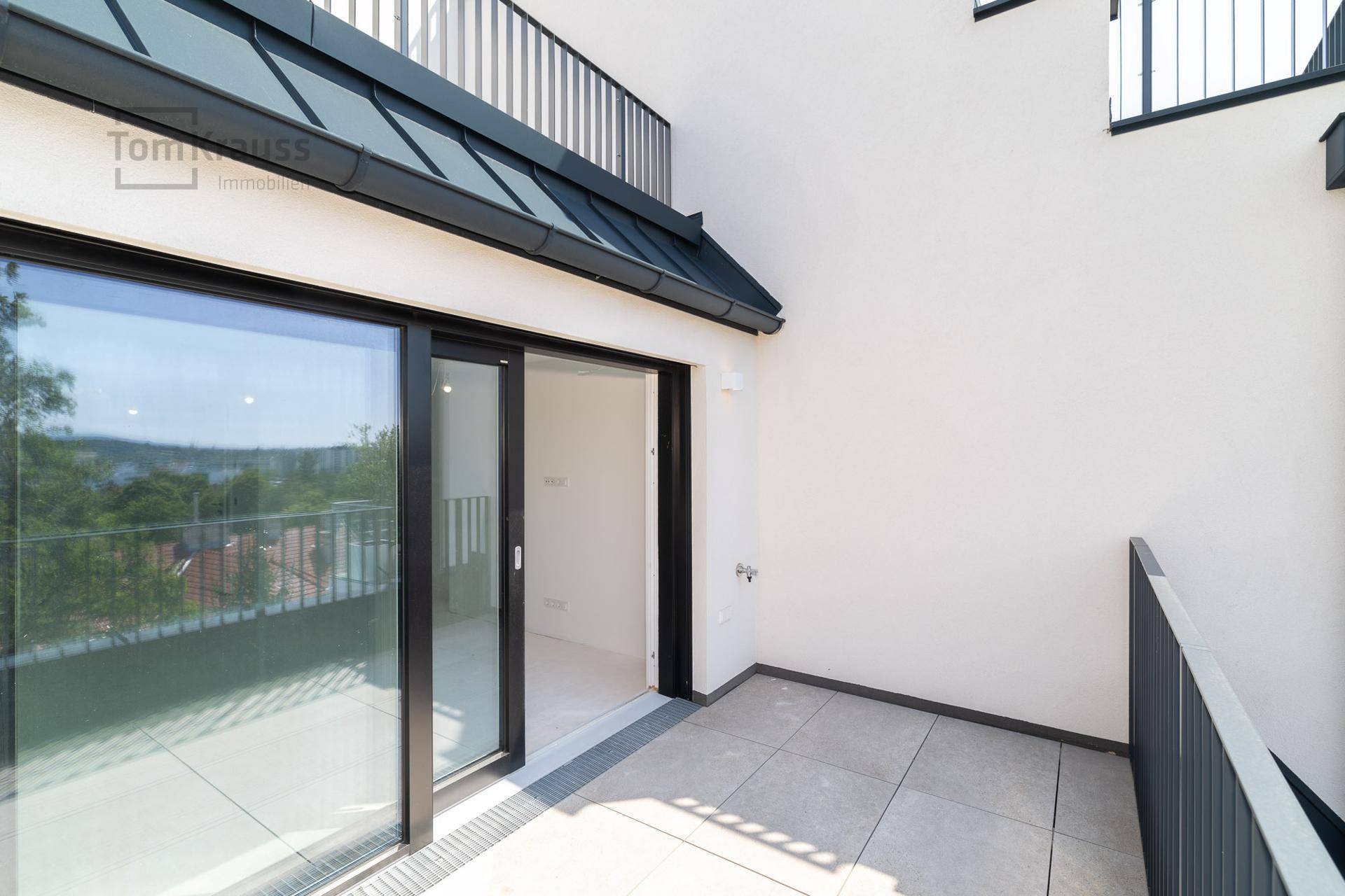Kleinerer Balkon mit Fliesenboden und Geländer, bietet Blick auf die Umgebung.