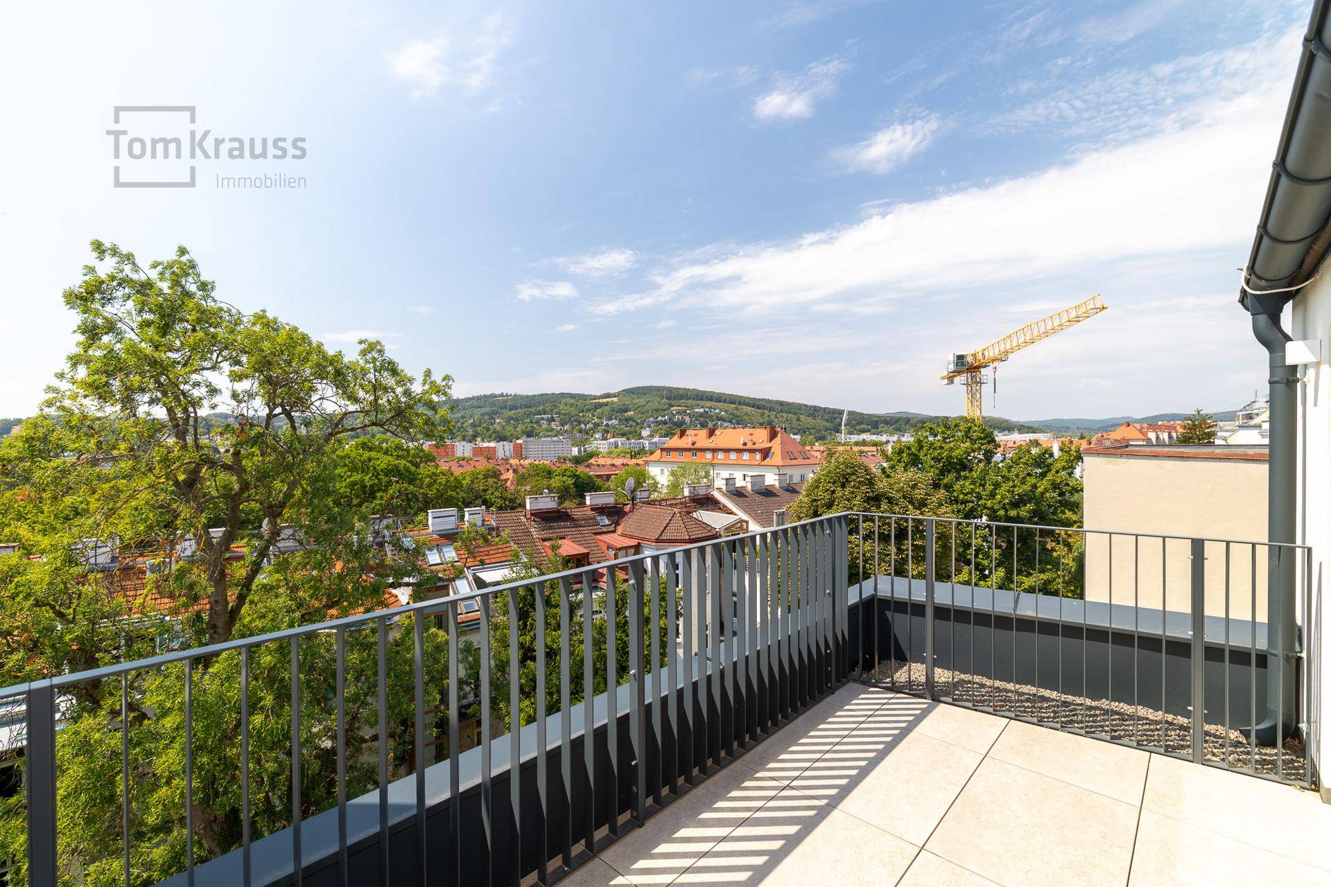 Leere Terrasse mit Fliesenboden und Geländer, bietet weite Aussicht.
