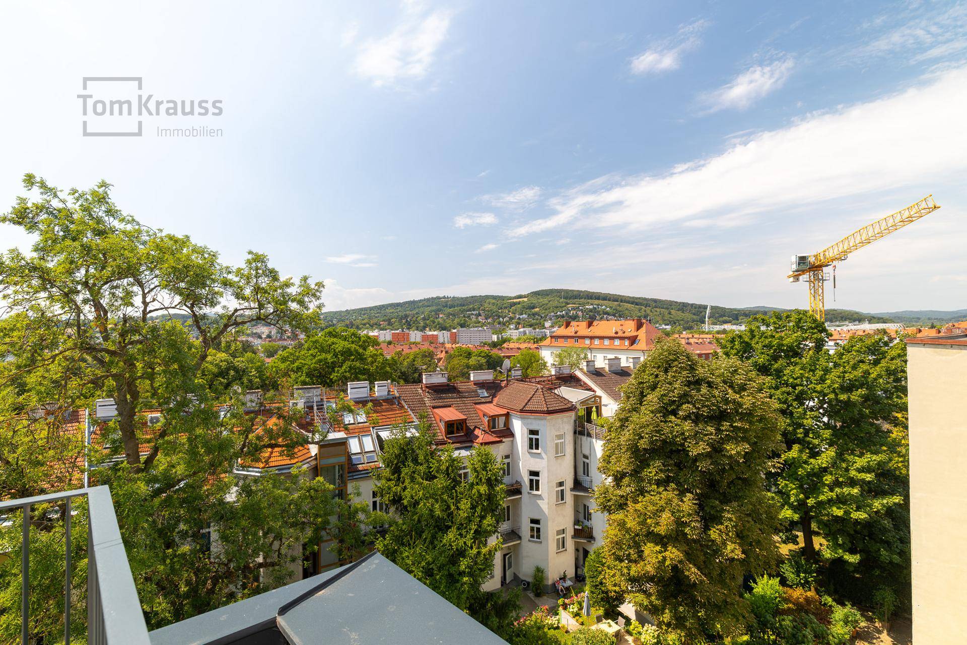 Weitläufiger Blick über die Stadt und grüne Hügel von einem oberen Stockwerk.