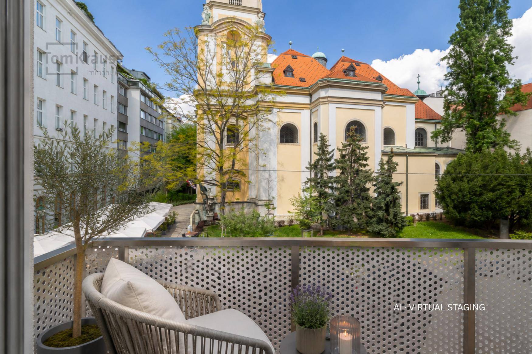 Möblierter Balkon mit Sitzgelegenheit und Blick auf eine historische Kirche und die Stadt.