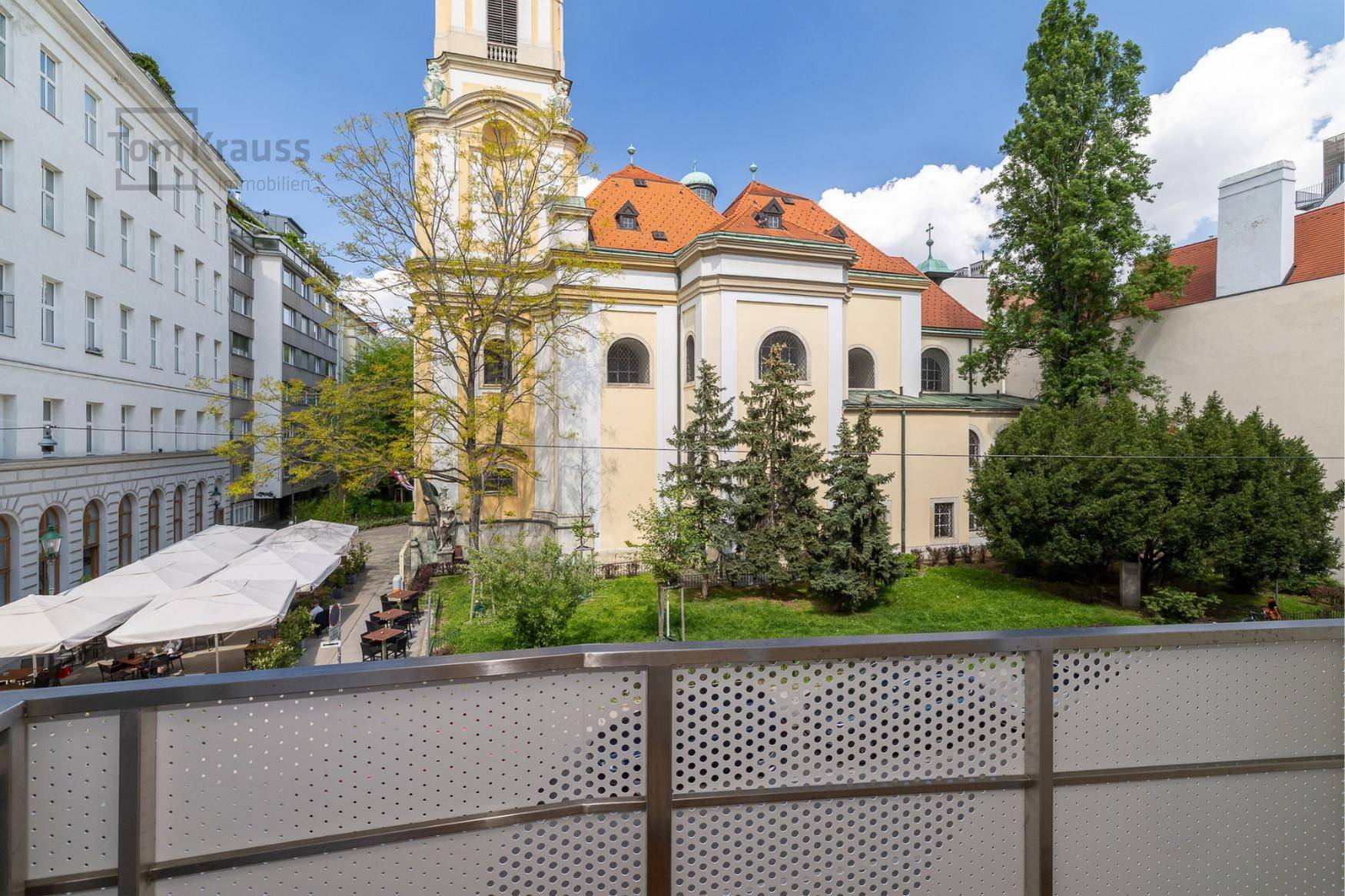 Blick von einem Balkon auf eine historische Kirche und die umliegende Stadtlandschaft.