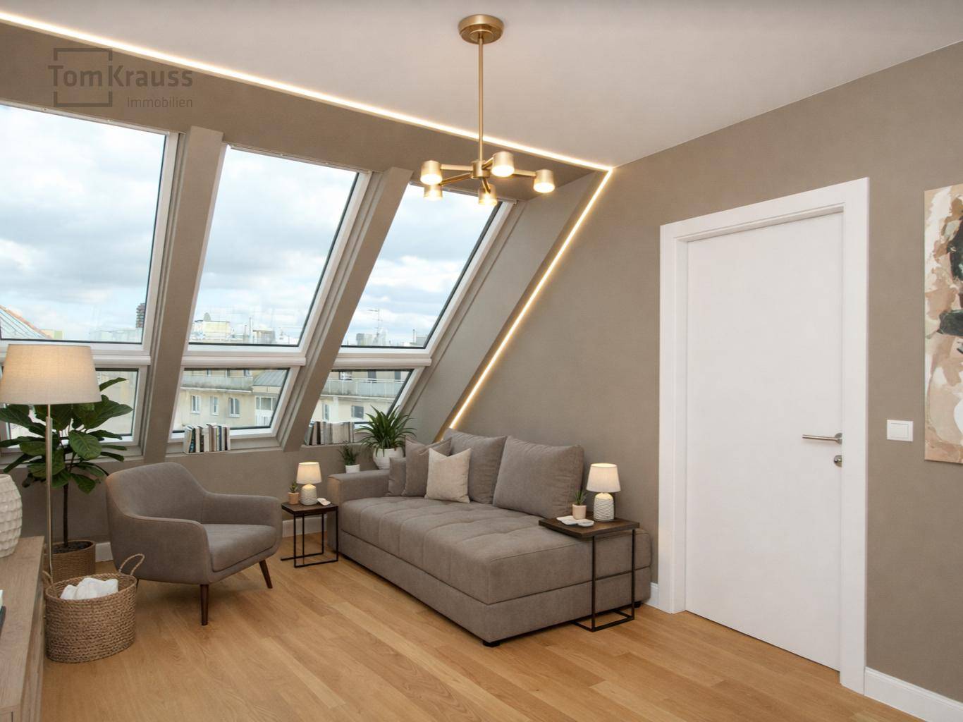 Helles Wohnzimmer im Dachgeschoss mit schrägen Wänden, großen Dachfenstern und modernem Mobiliar.