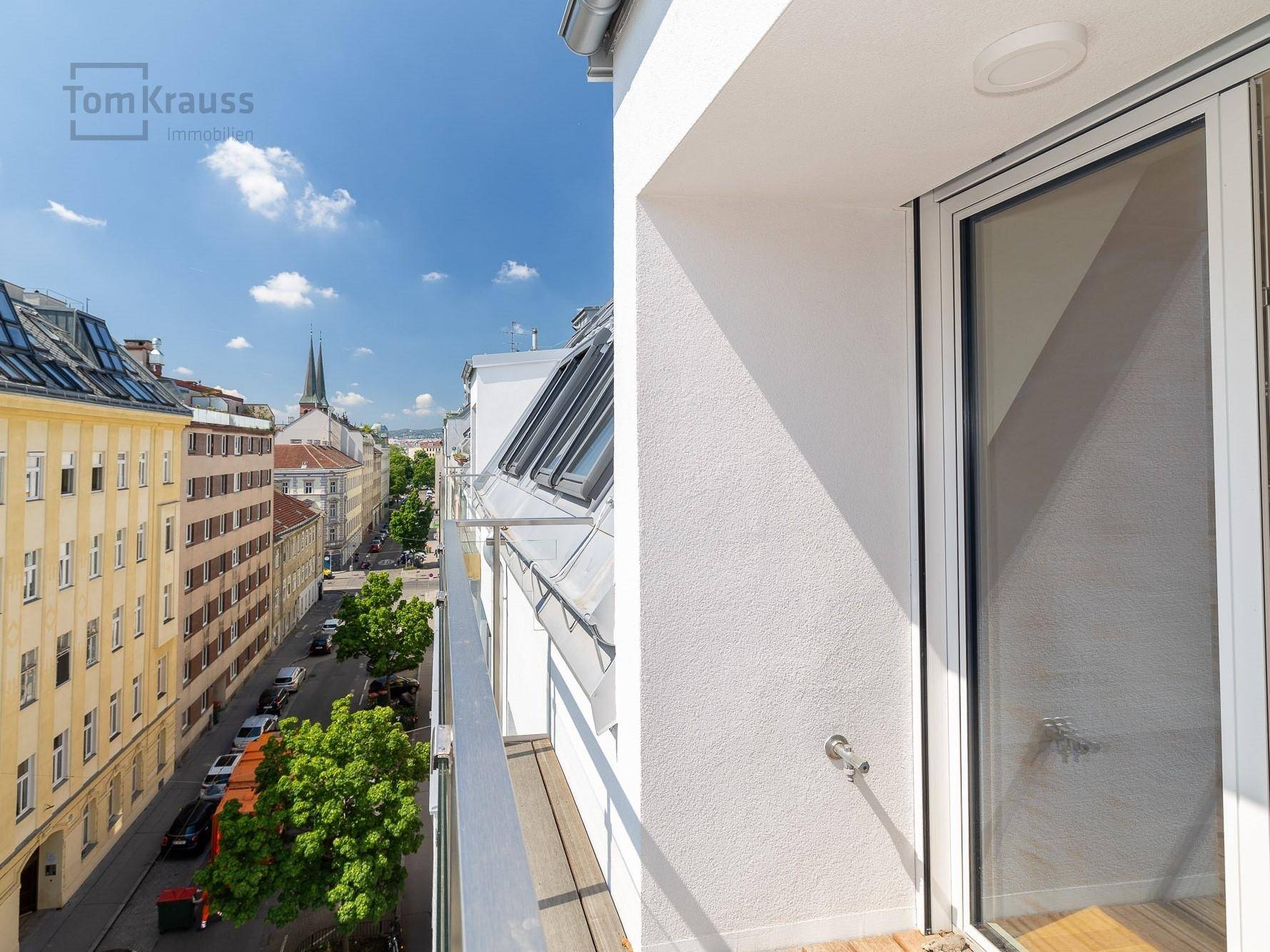 Leerer Balkon mit Holzboden und weitem Blick über die belebte Stadtstraße.
