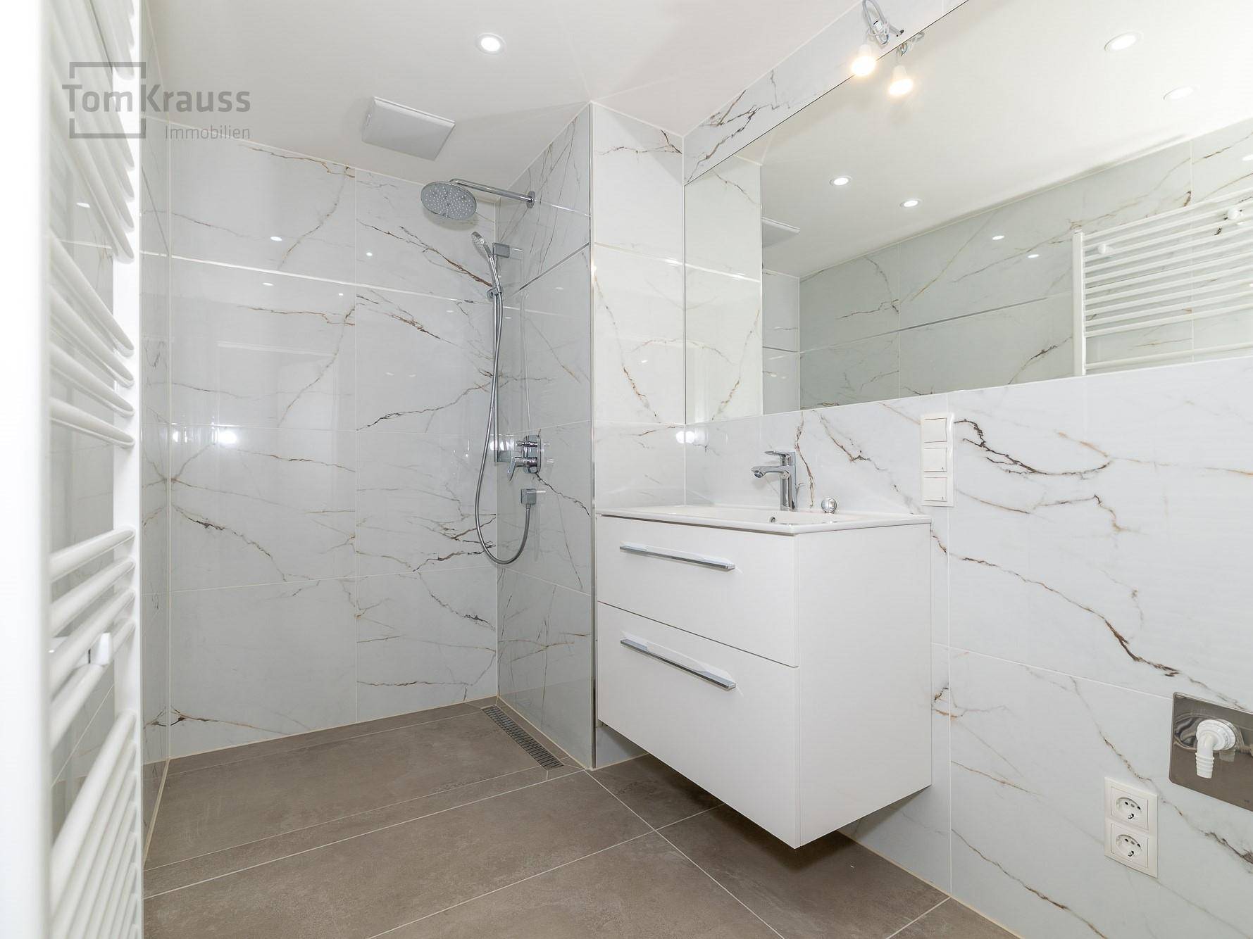 Modernes Badezimmer mit begehbarer Dusche, Waschbecken und großem Spiegel.