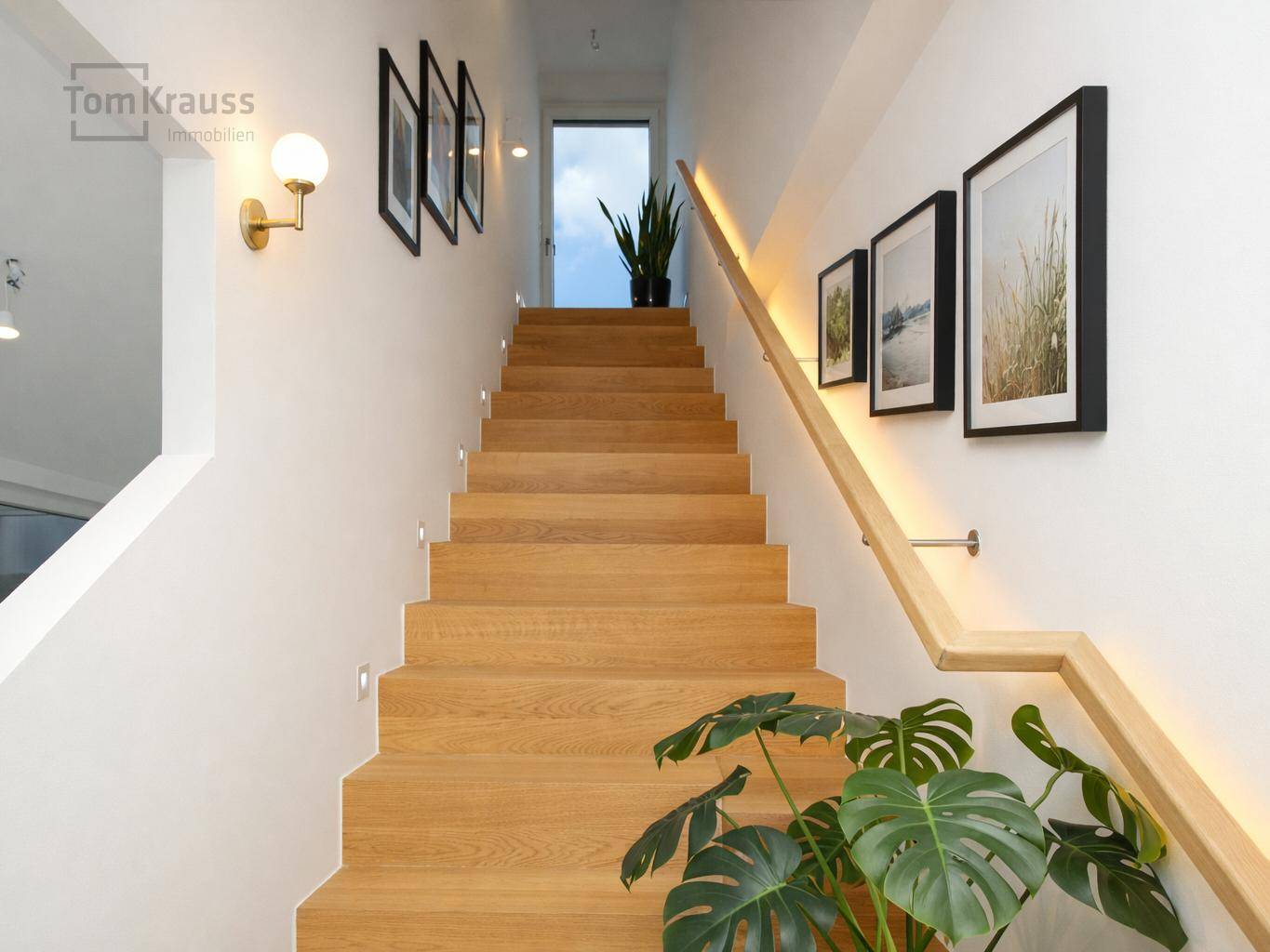 Moderne Holztreppe mit elegantem Handlauf, integrierter Beleuchtung und Wanddekoration.