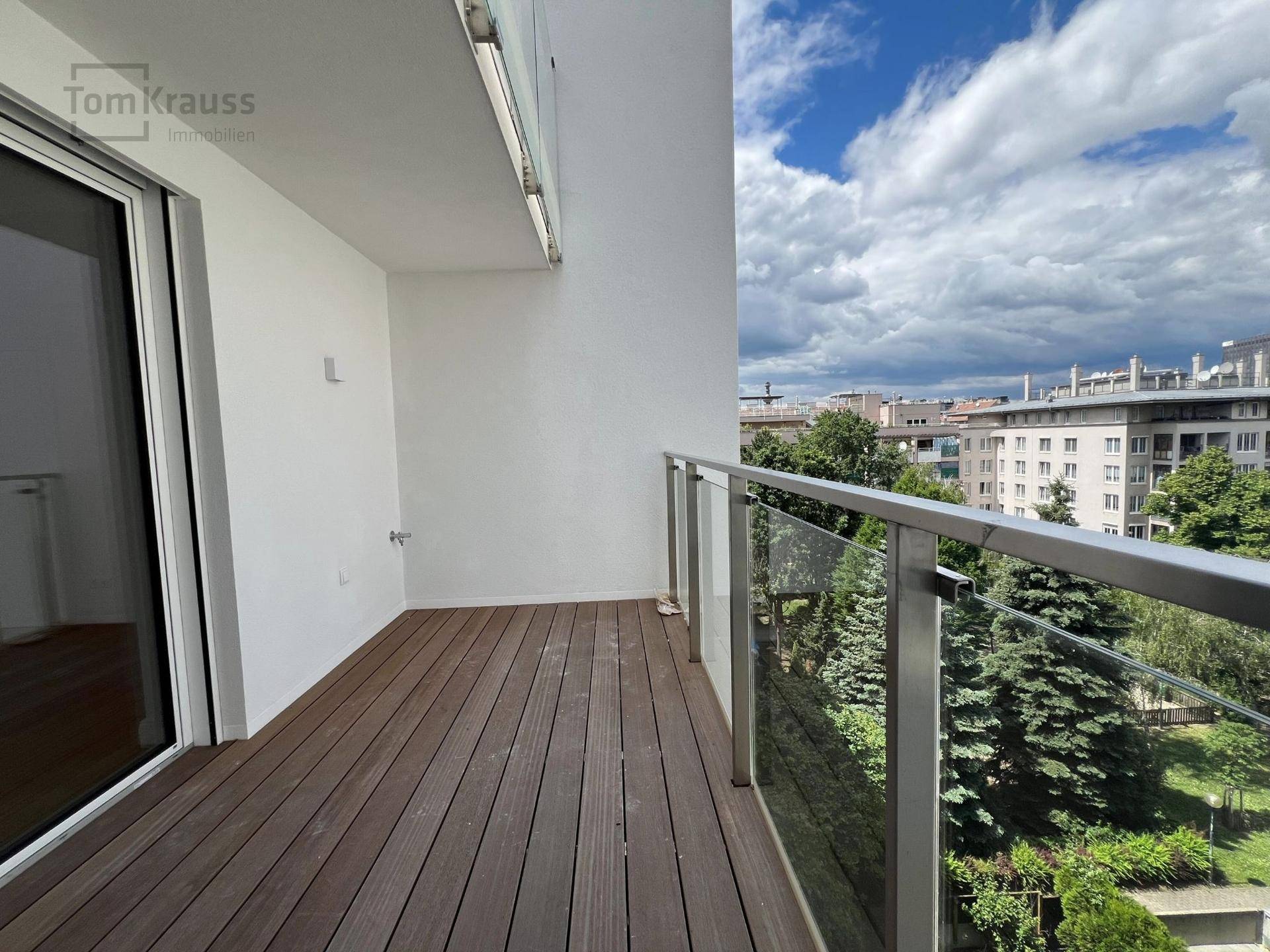 Geräumiger Balkon mit Holzboden und Glasgeländer, bietet einen weiten Blick über die Umgebung.