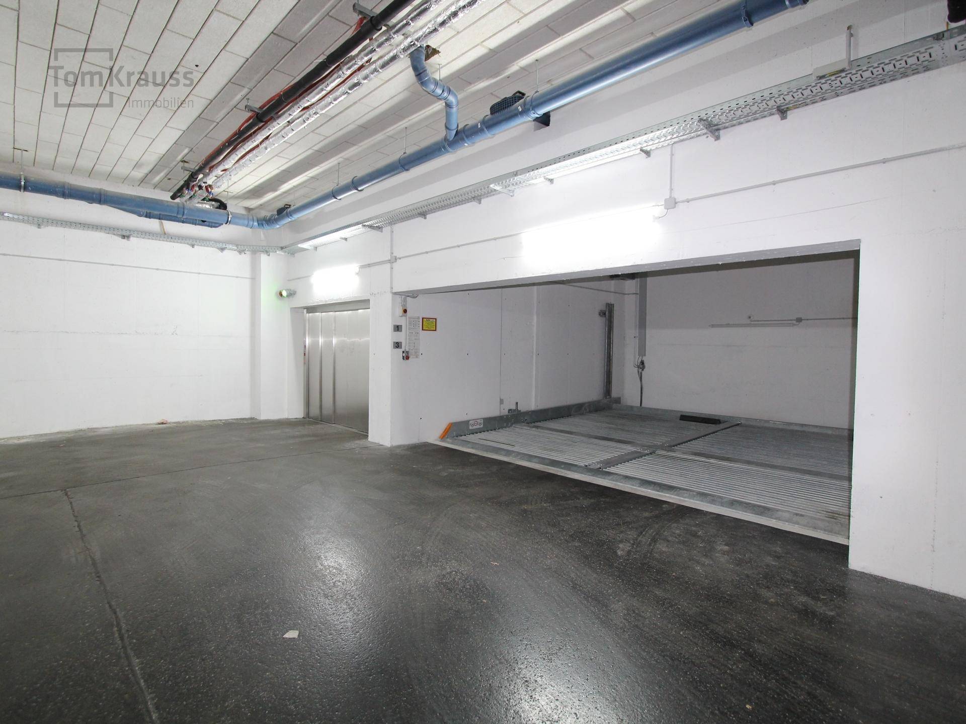 Tiefgarage mit automatischem Parksystem und Zugang zum Aufzug.