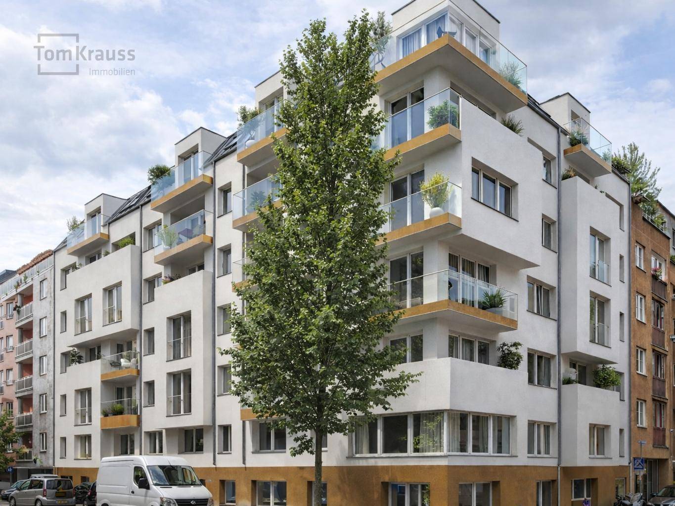 Modernes Mehrfamilienhaus mit weißer Fassade, vielen Balkonen und großen Fenstern in städtischer Umgebung.