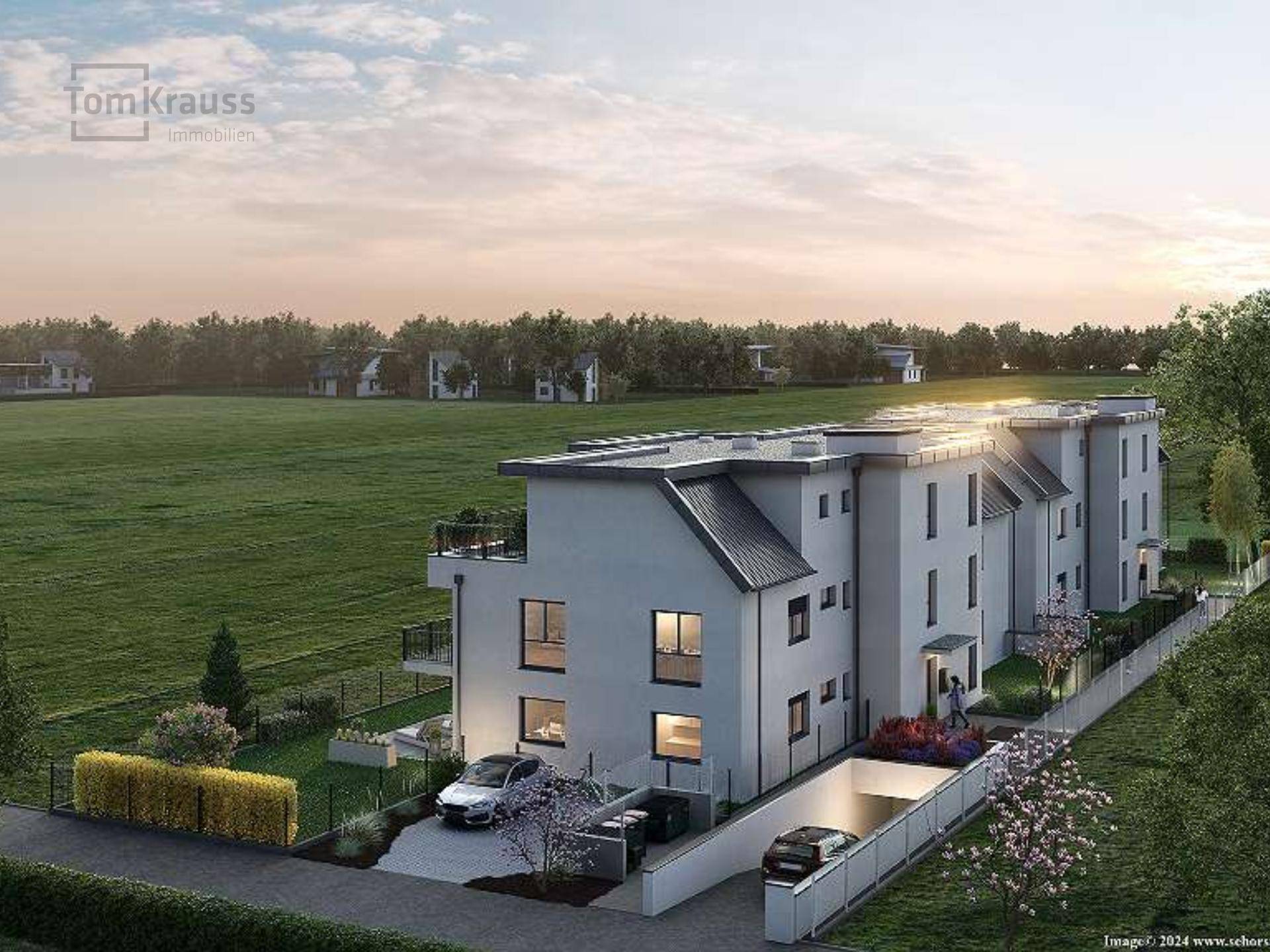 Luftaufnahme der modernen Wohnanlage mit Reihenhäusern, Gärten und Parkplätzen bei Sonnenuntergang.