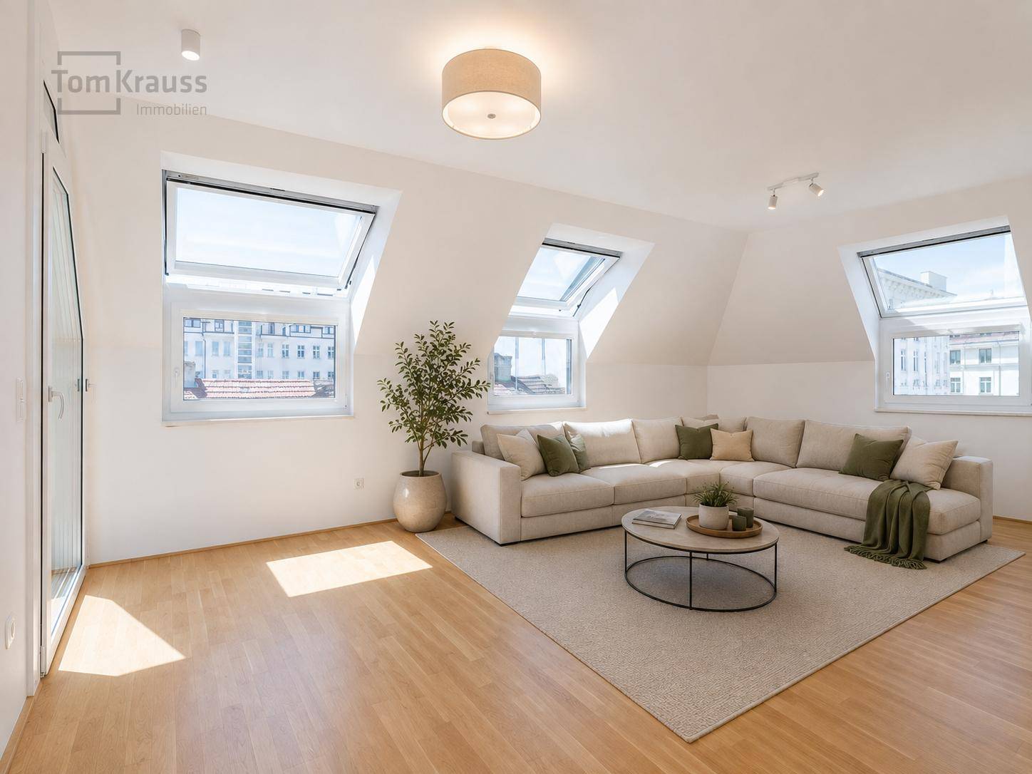 Helles Wohnzimmer im Dachgeschoss mit beigem Sofa, Couchtisch und Dachfenstern.