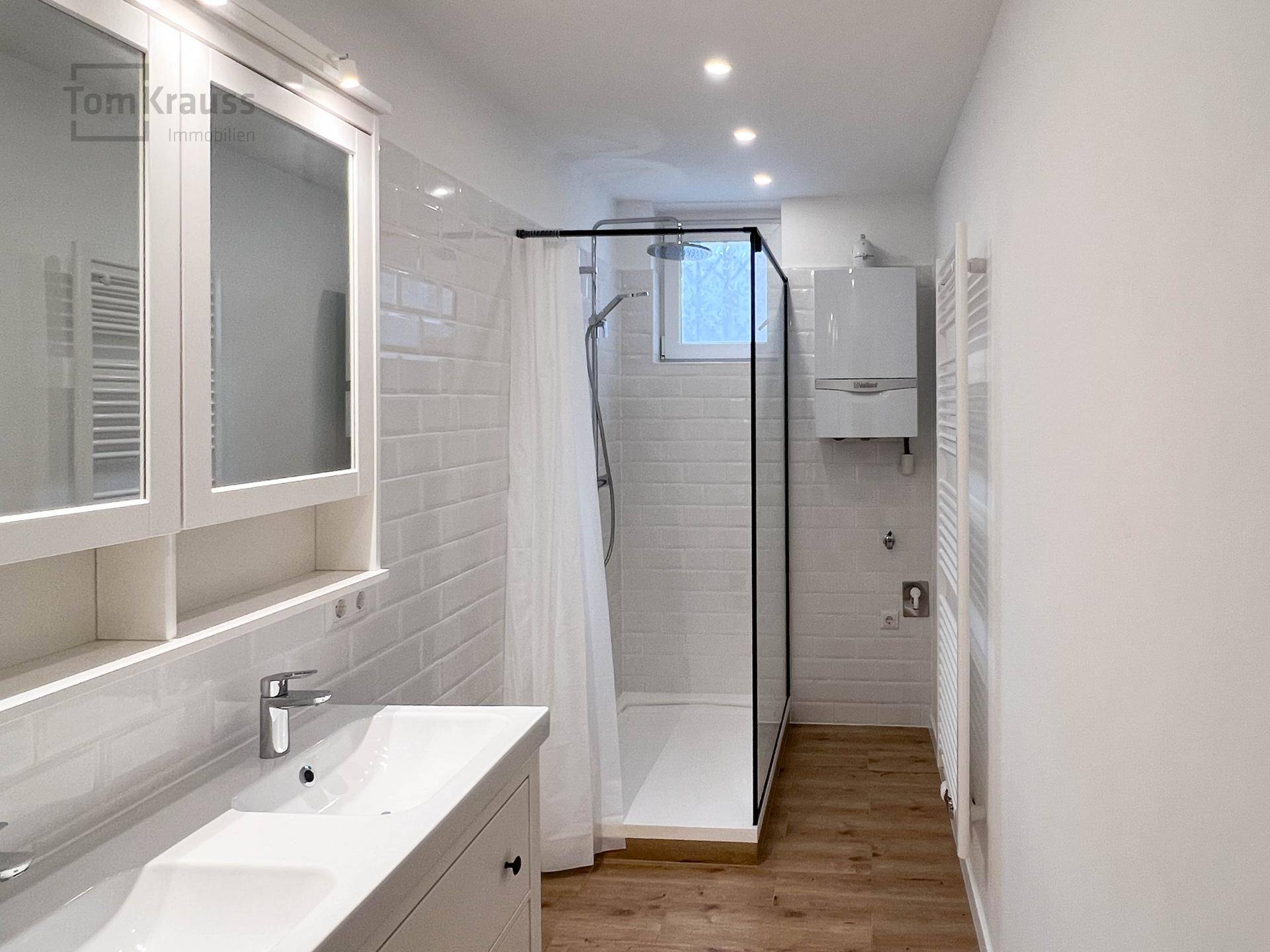 Modernes Badezimmer mit Dusche, Waschbecken und weißen Fliesen.