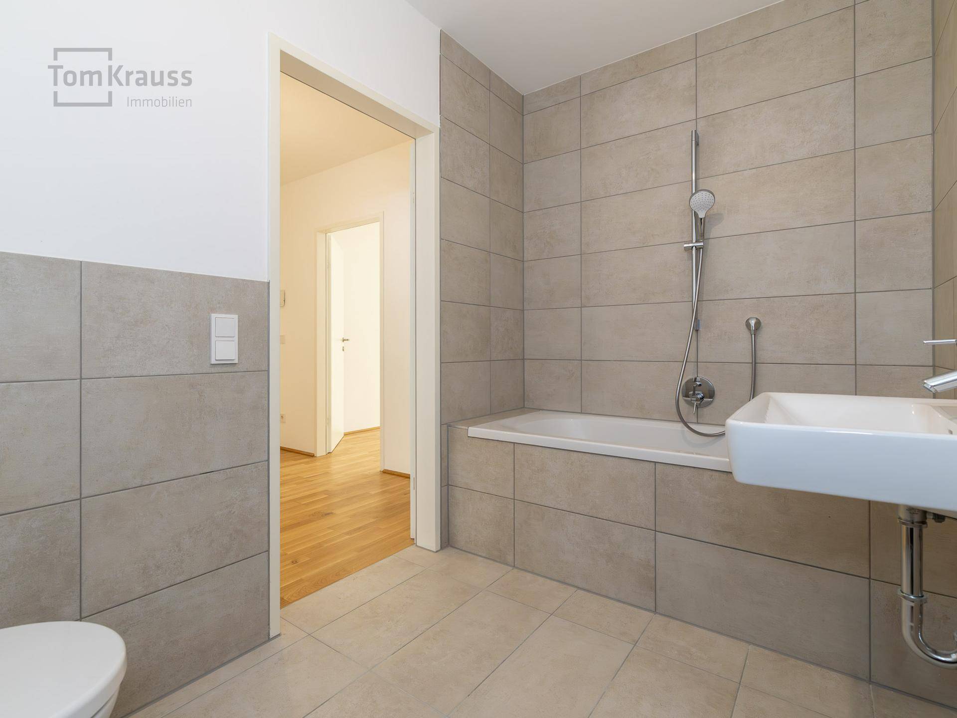 Helles Badezimmer mit Badewanne, modernen Fliesen und einfacher, funktionaler Ausstattung.