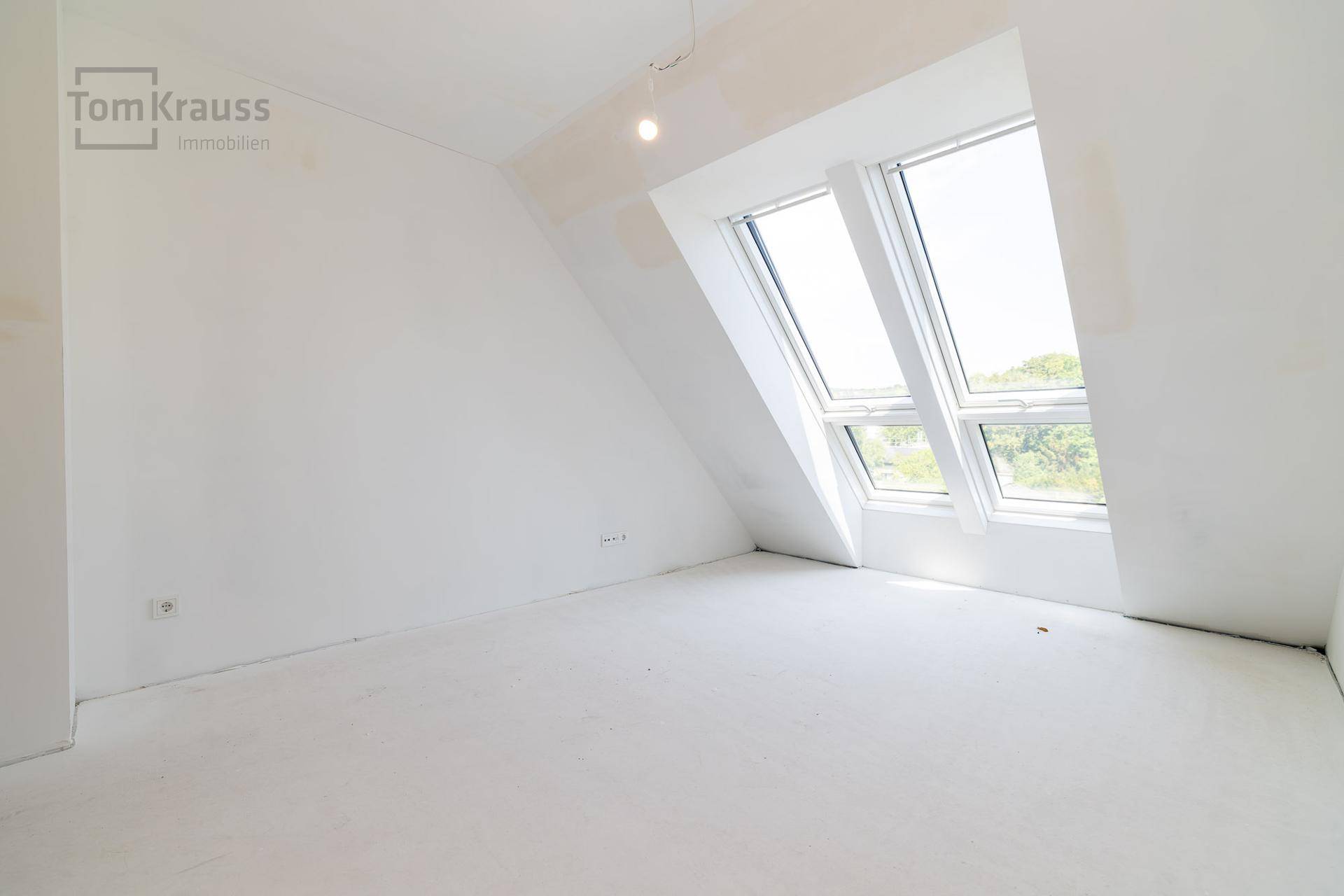 Heller, unmöblierter Raum mit Dachfenstern und Blick ins Grüne, ideal als Schlafzimmer.