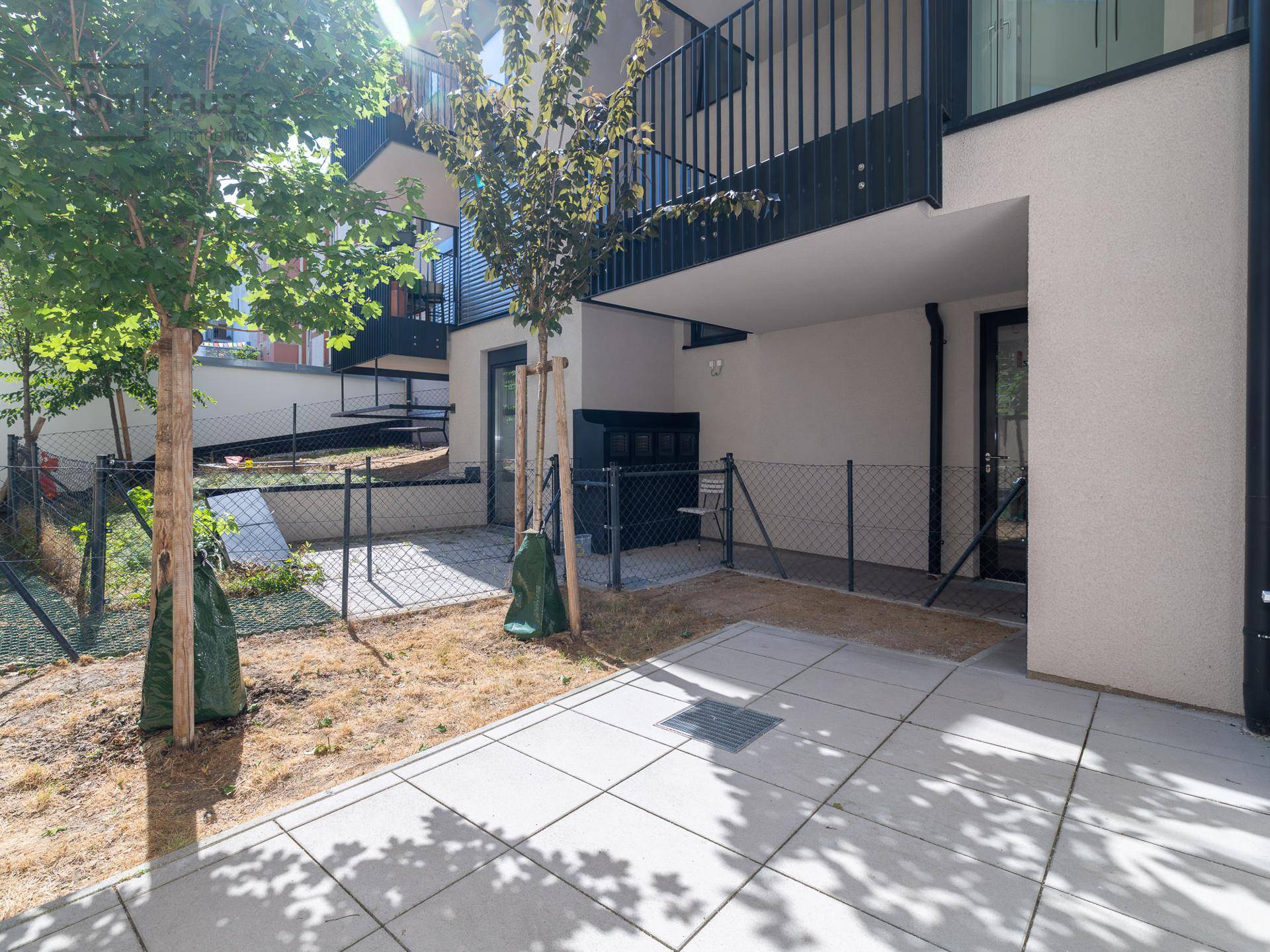 Unmöblierte Terrasse mit angrenzendem Gartenbereich und Zaun, bereit zur individuellen Gestaltung.