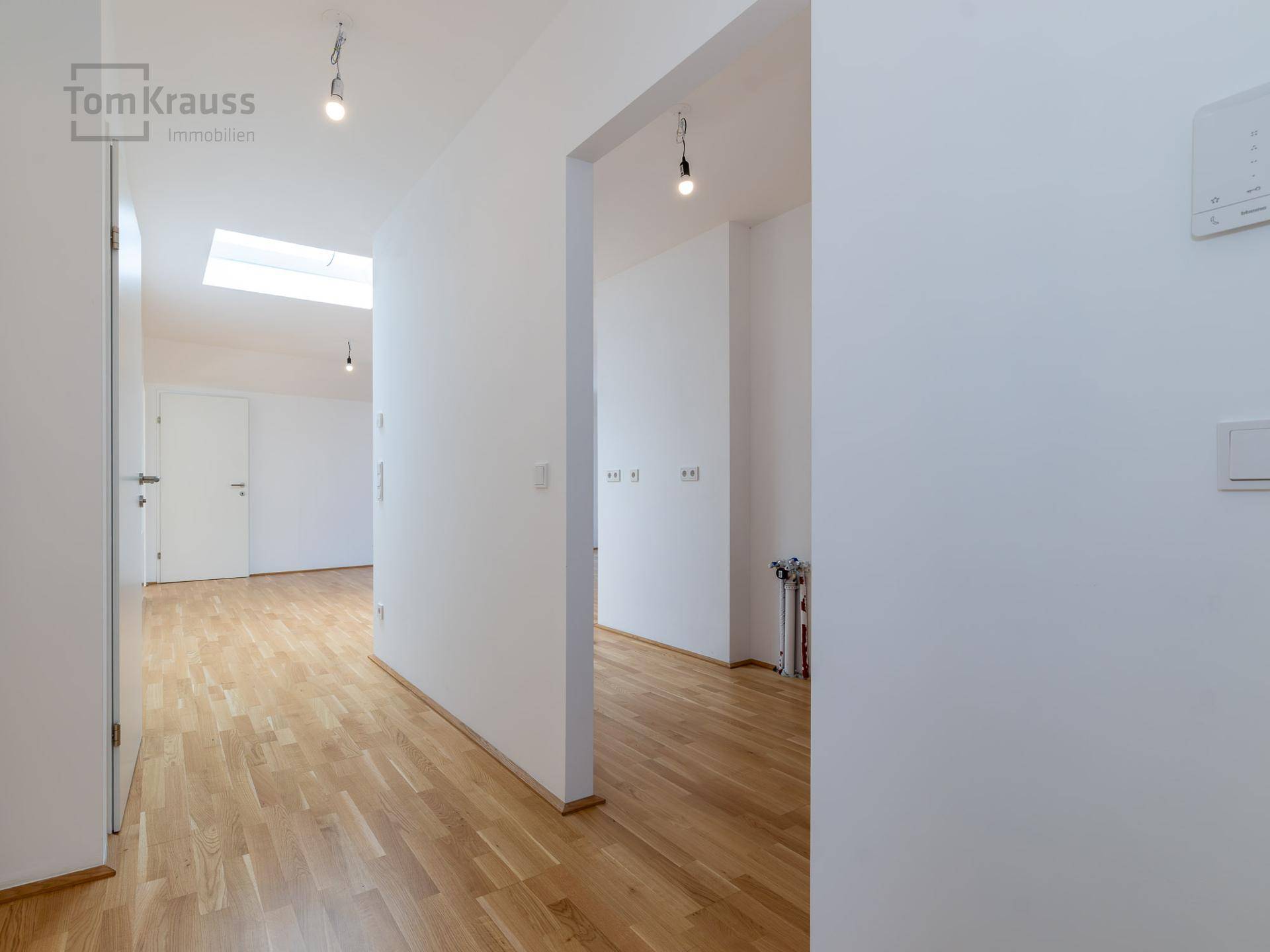 Geräumiger, leerer Flur mit hellem Holzboden und Dachfenster, bietet viel natürliches Licht.