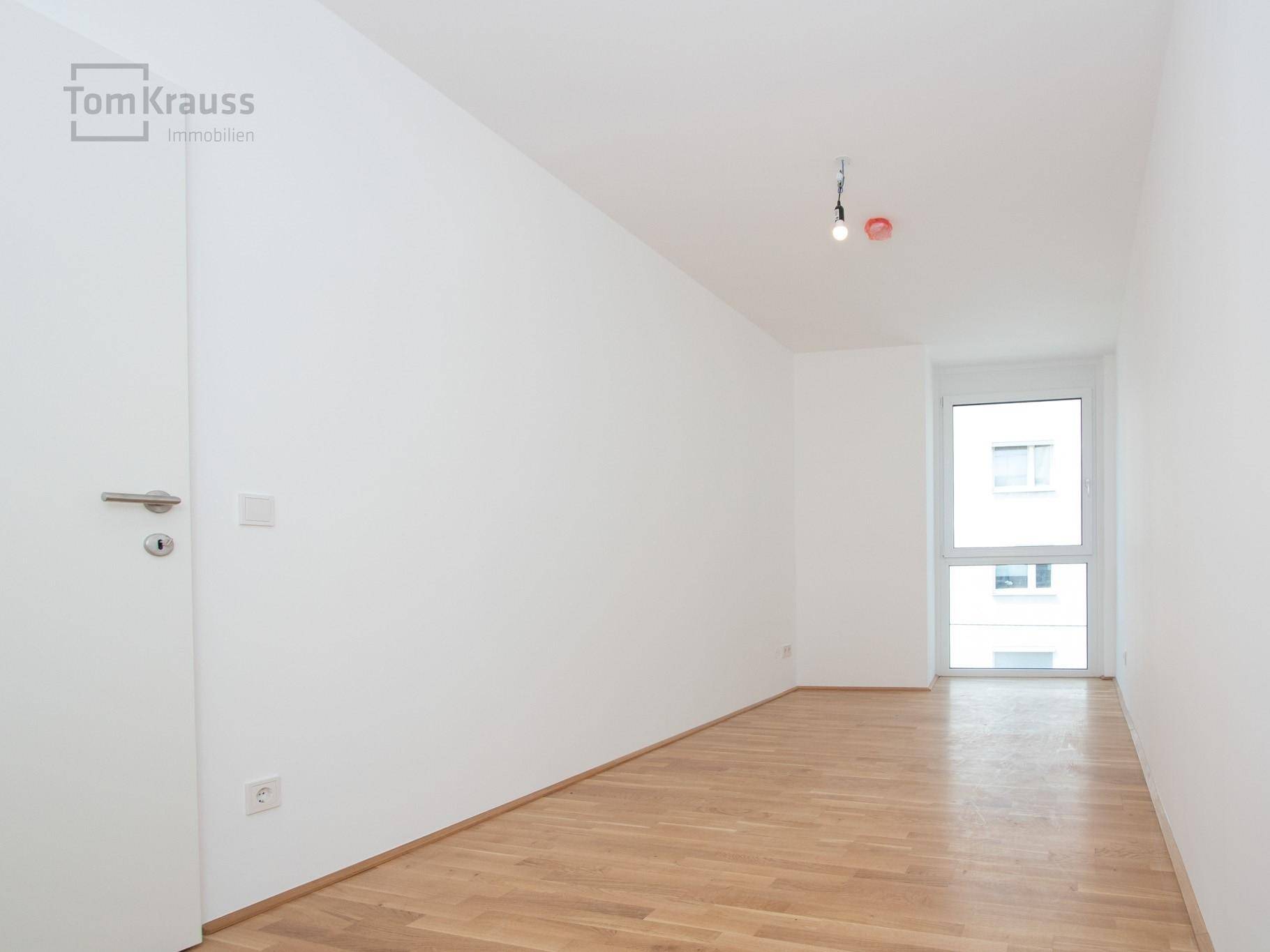 Heller, leerer Raum mit Parkettboden und einem Fenster, bereit zur individuellen Einrichtung.
