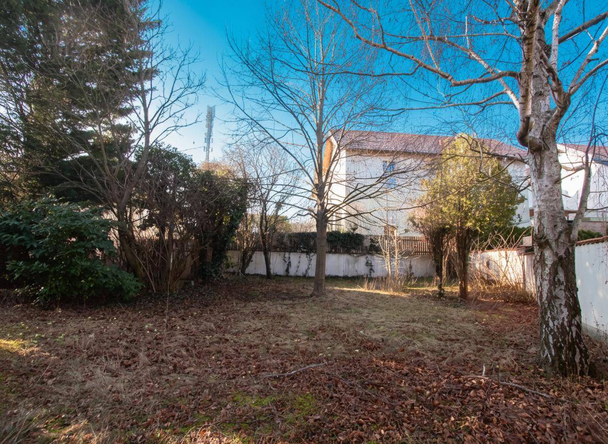 Großer, naturbelassener Garten mit mehreren Bäumen und einem Zaun im Hintergrund.