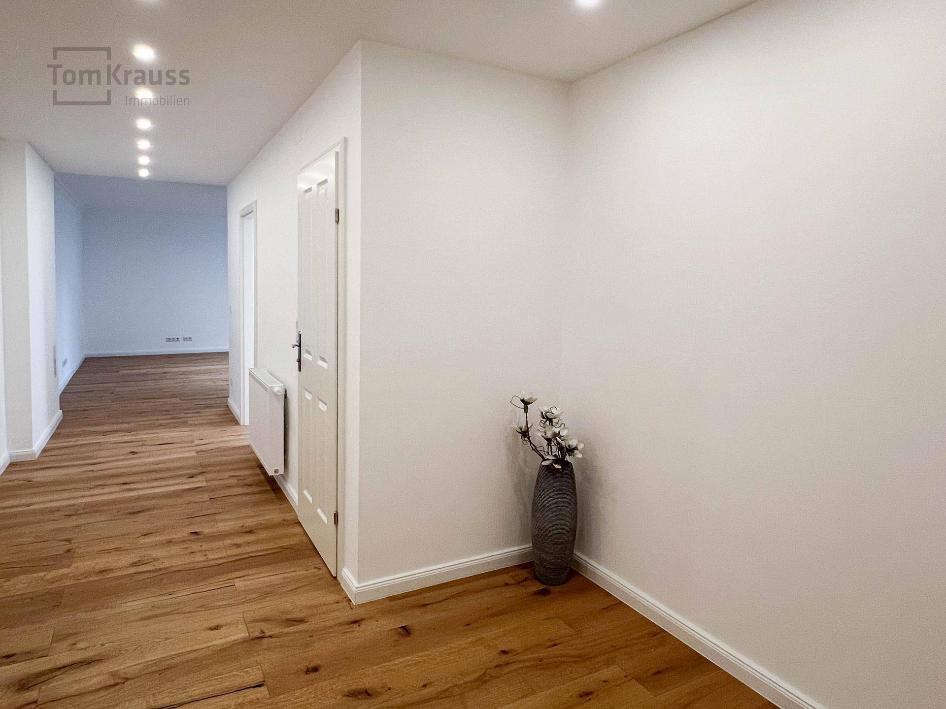 Heller Flur mit Holzboden und Einbaustrahlern an der Decke.