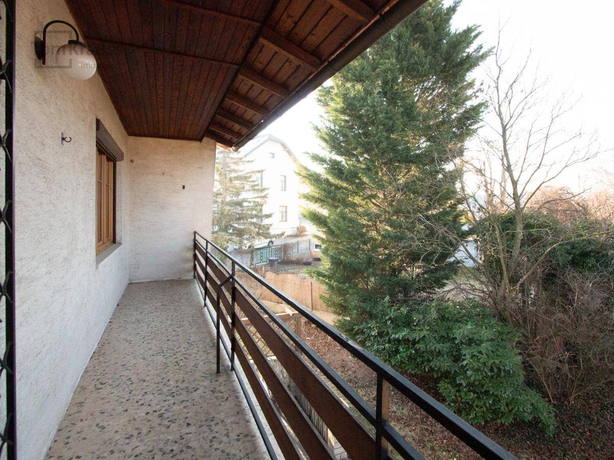 Alter Balkon mit Metallgeländer und Blick ins Grüne, bereit für eine Neugestaltung.