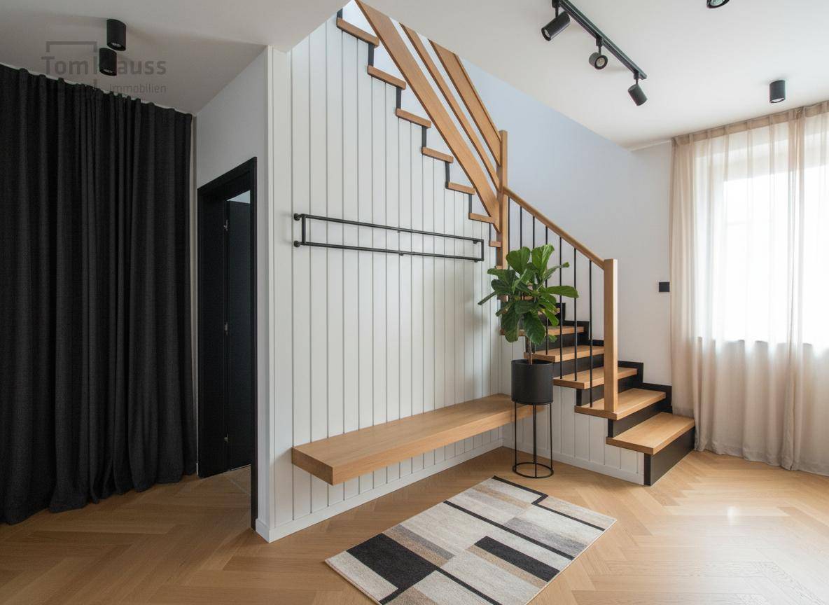 Moderner Eingangsbereich mit Holztreppe, weißer Vertäfelung, Sitzbank und schwarzer Schienenbeleuchtung.